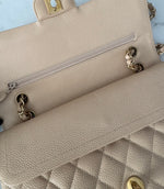 Load image into Gallery viewer, Close-up of a beige handbag with a zipper and gold hardware on a light blue background

