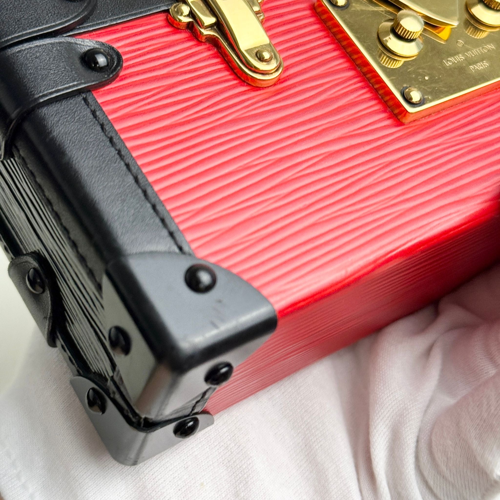 Close-up of a red suitcase with black handle and gold accents on a white background