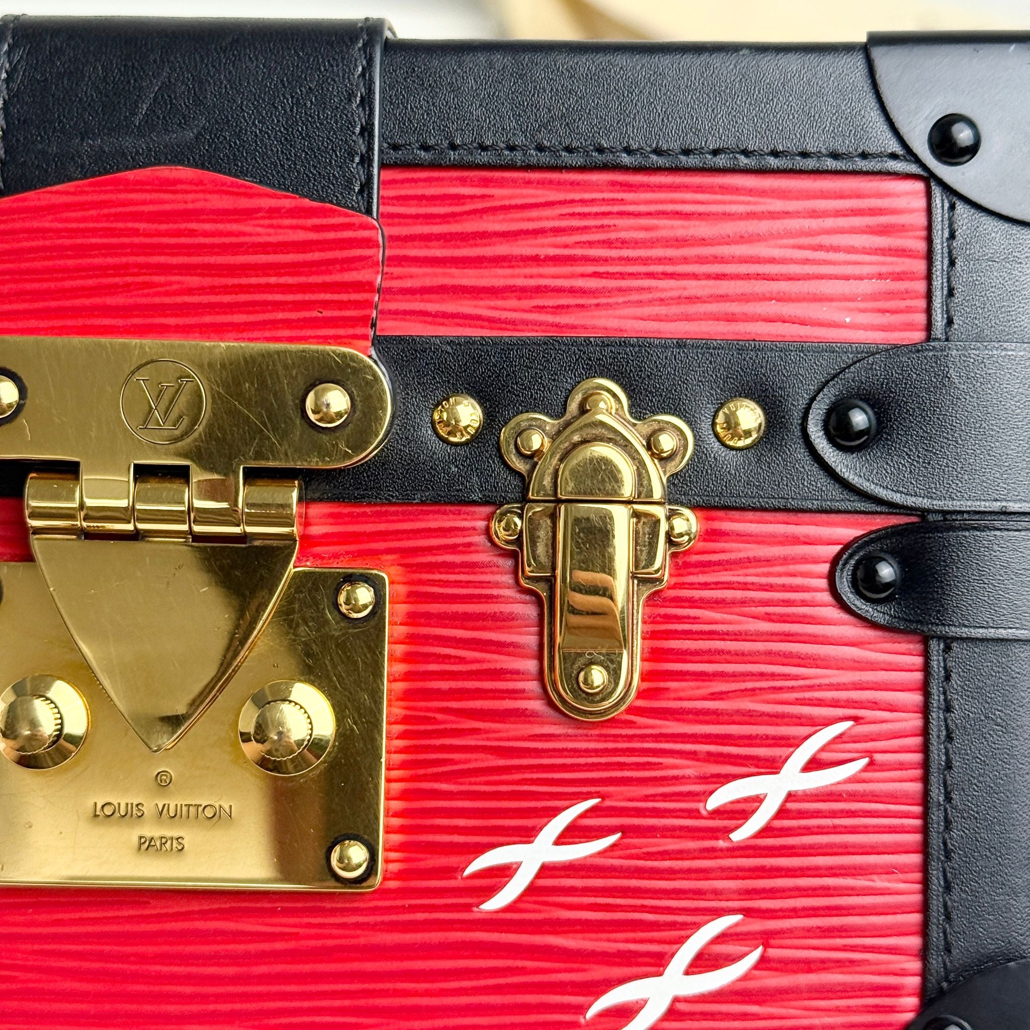 Close-up of a red and black Louis Vuitton bag with gold hardware.