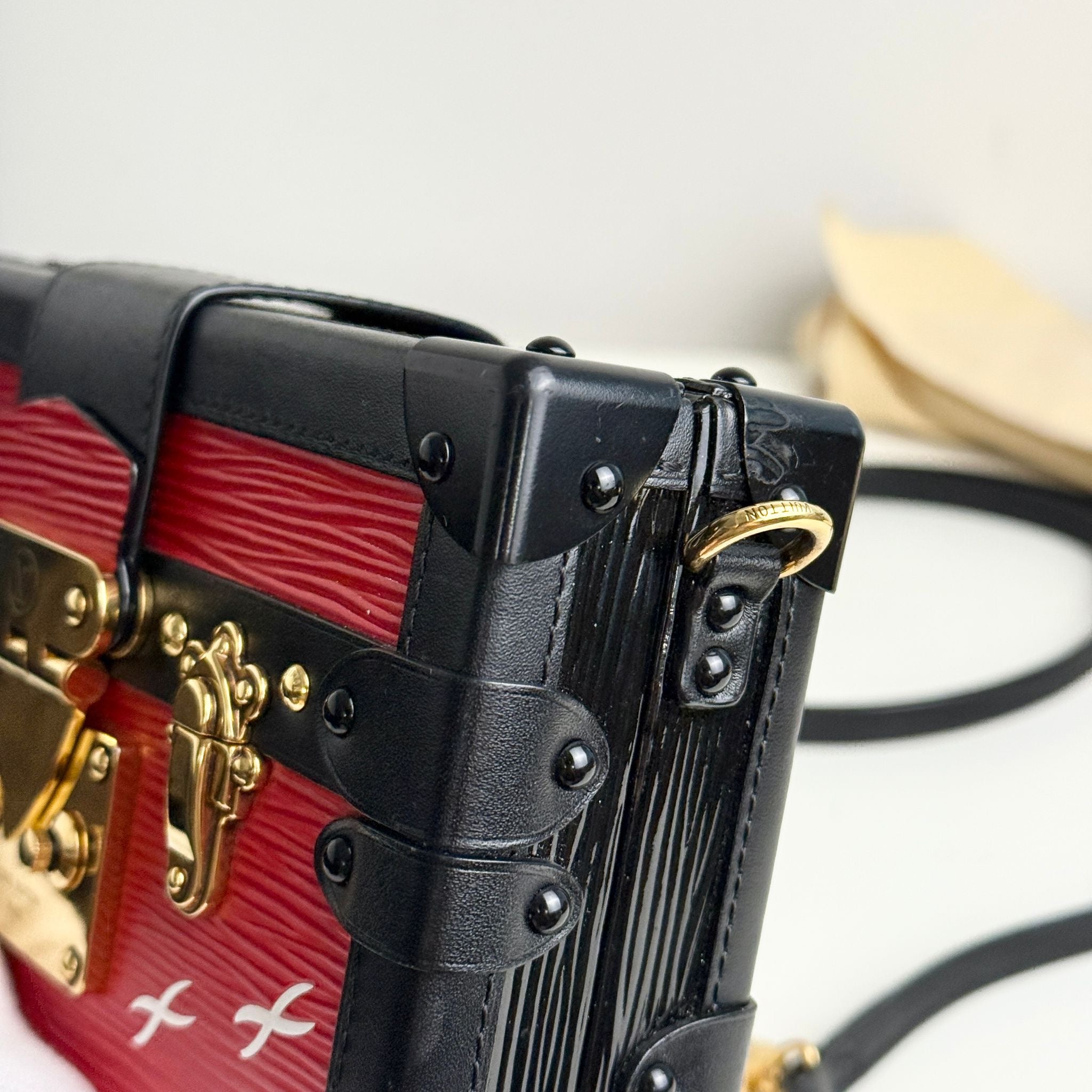 Close-up of a red and black handbag with gold accents on a blurred background