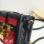 将图片加载到图库查看器，Close-up of a red and black handbag with gold accents on a blurred background

