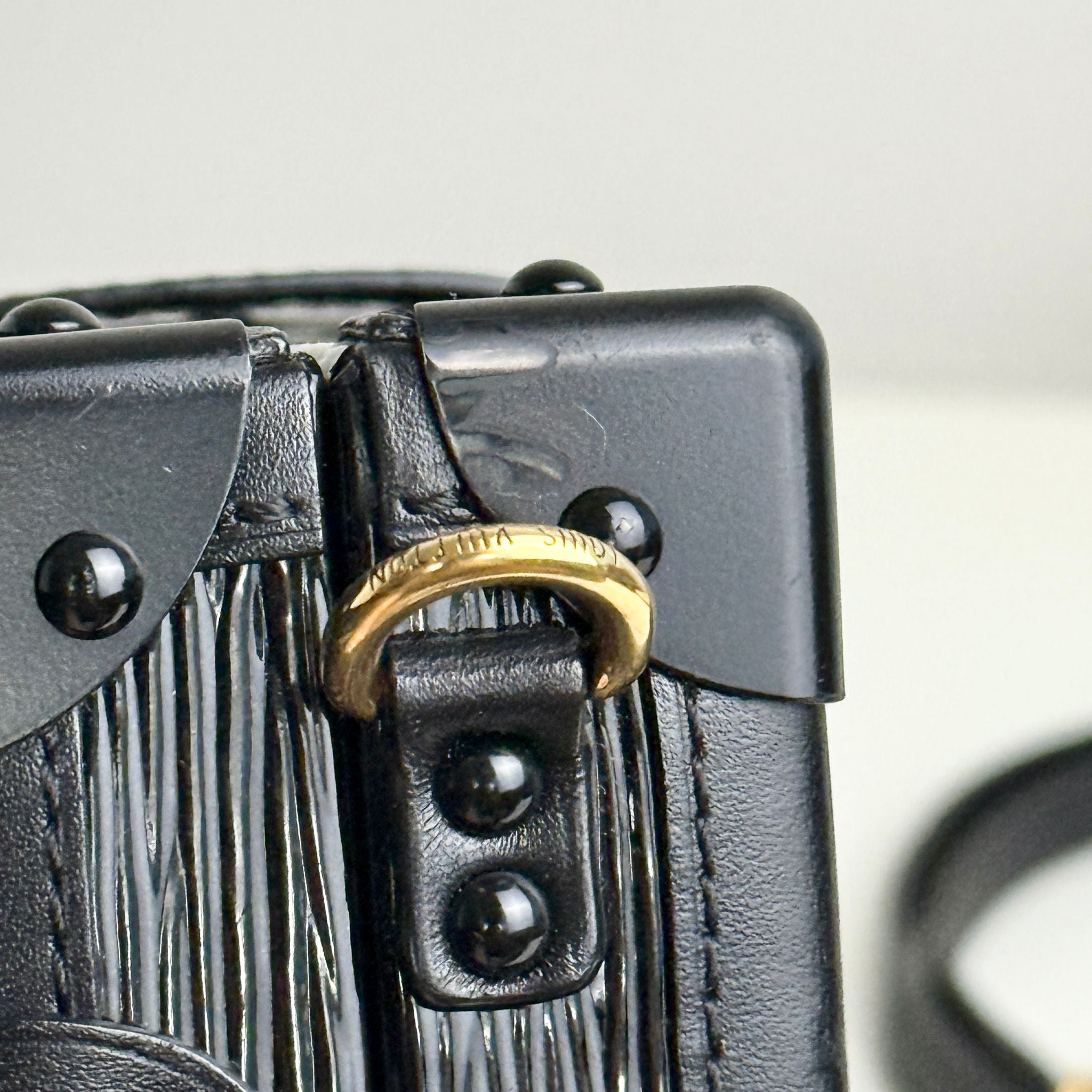 Close-up of a black leather bag with gold hardware on a blurred background