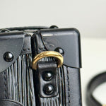 将图片加载到图库查看器，Close-up of a black leather bag with gold hardware on a blurred background
