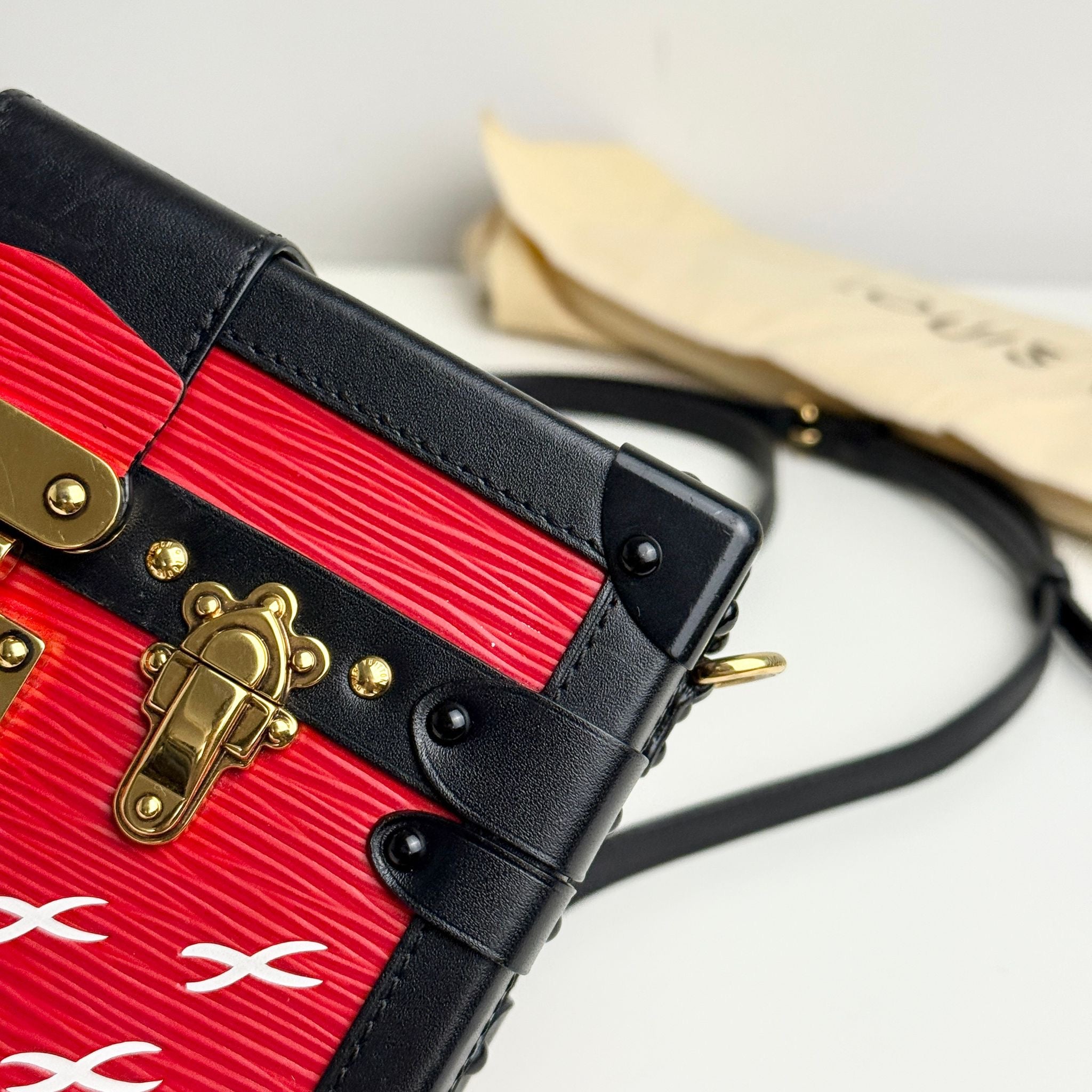 Red and black handbag with gold accents on a light gray background