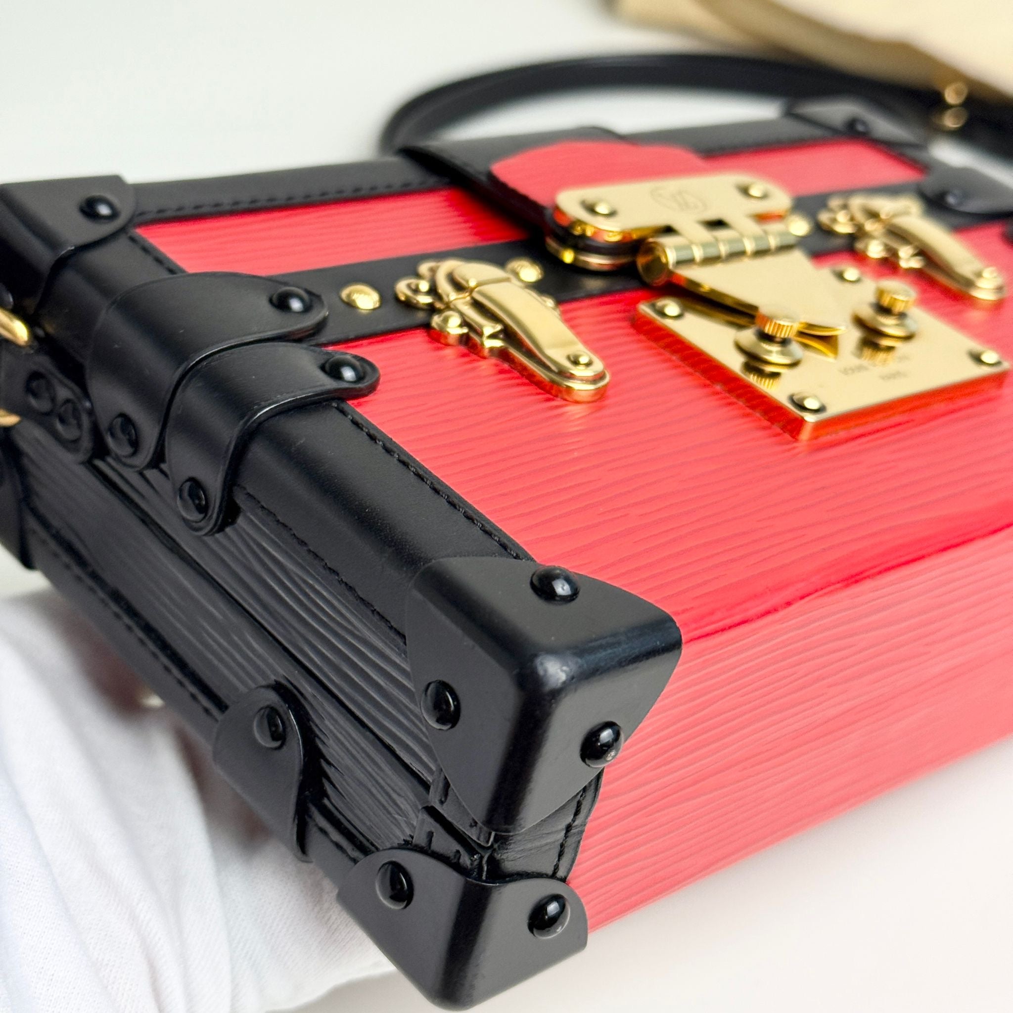 Red suitcase with black accents and gold locks on a white background