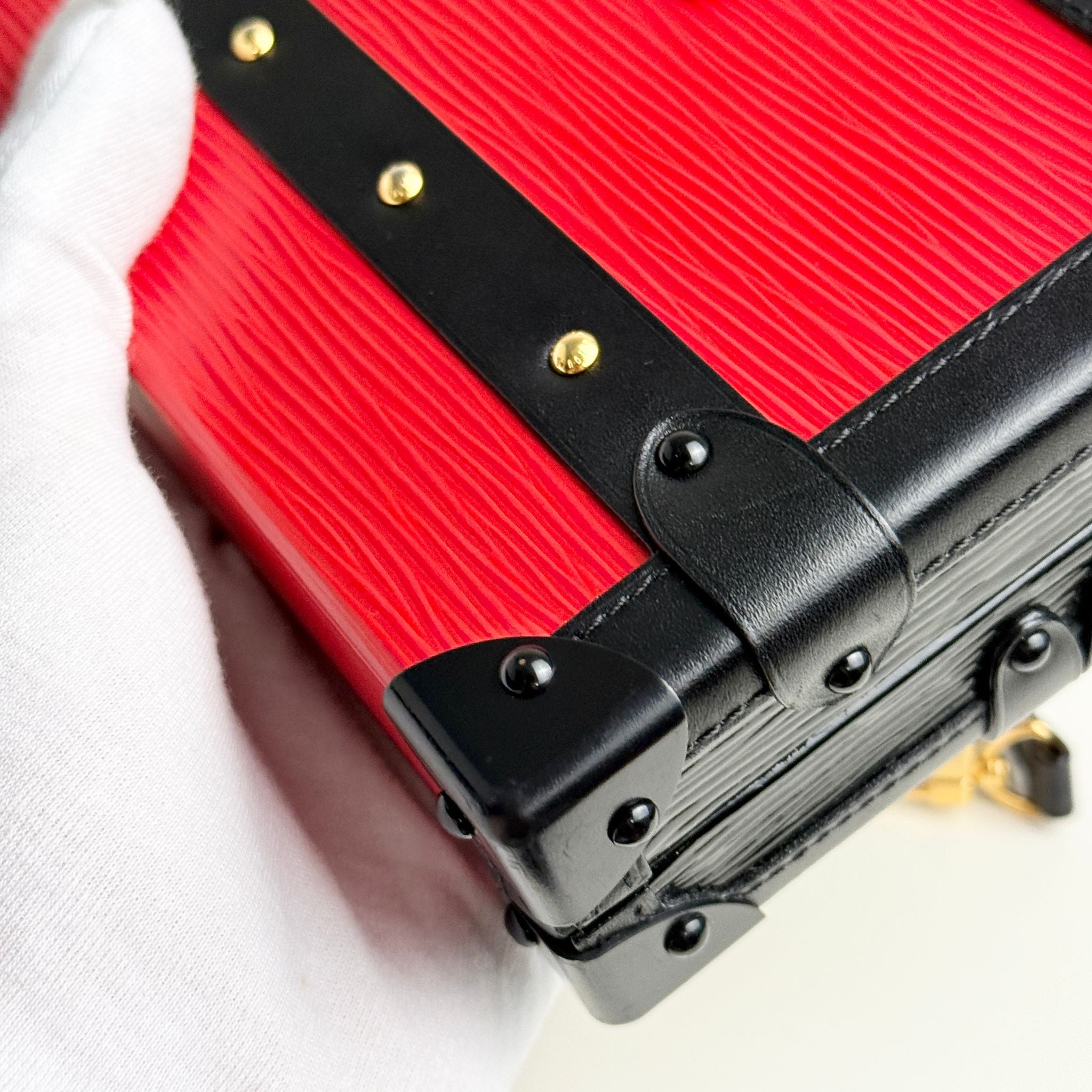 Red suitcase with black handle and gold accents on a white background