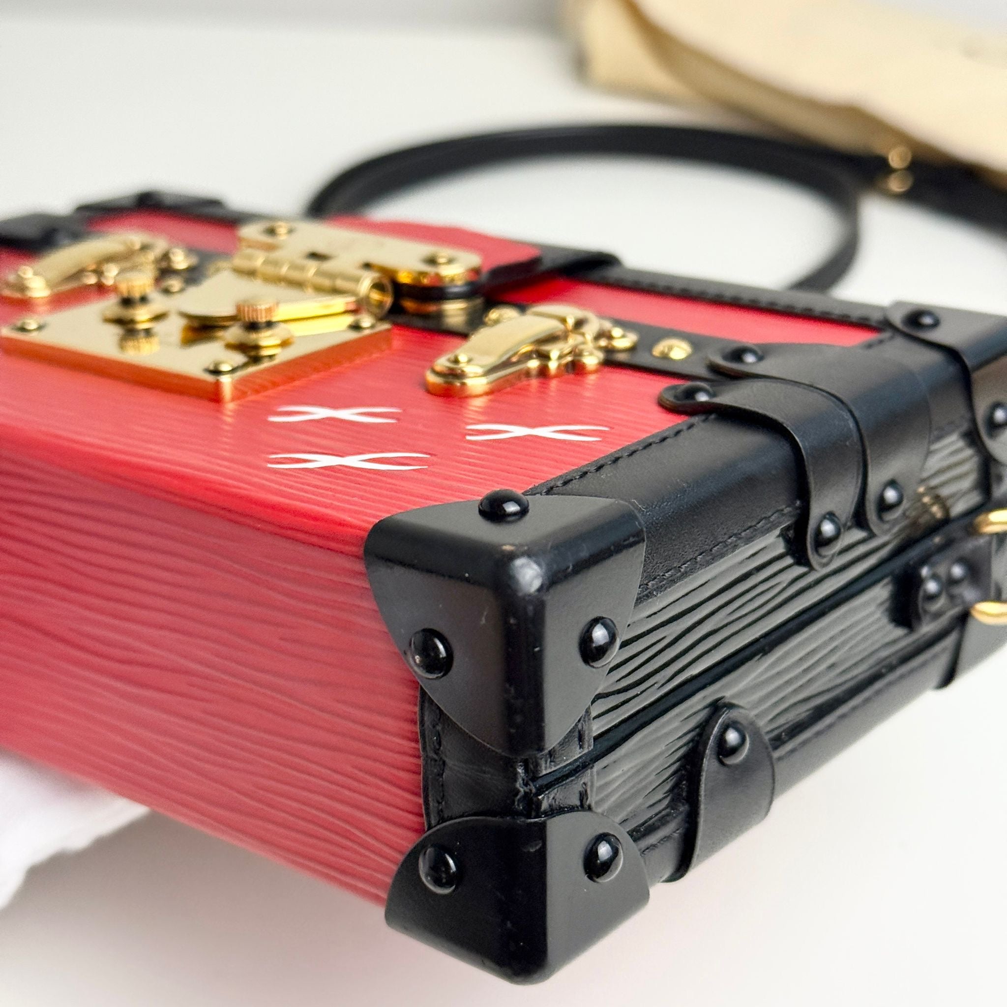 Close-up of a red and black handbag with gold accents on a white background
