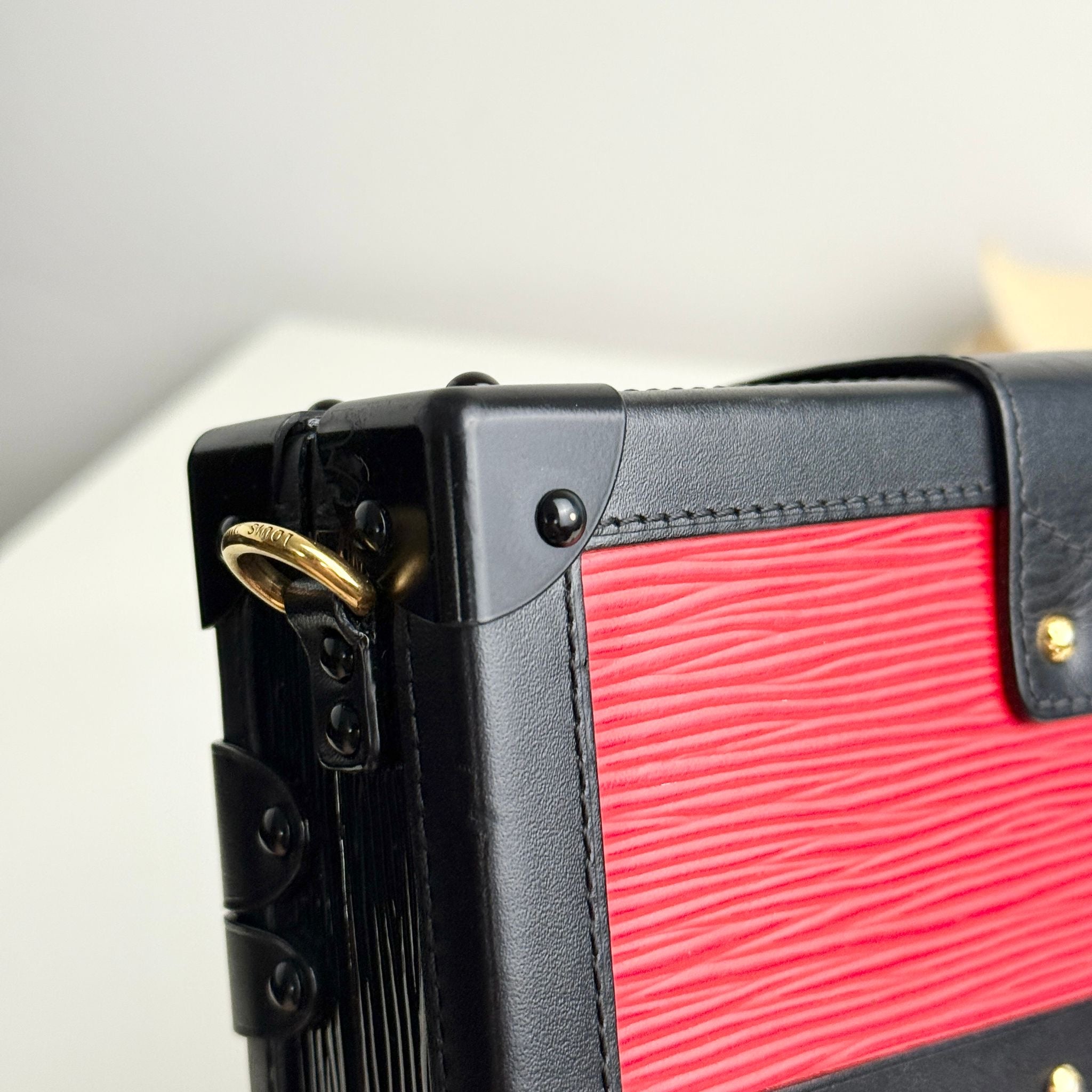 Close-up of a black and red textured suitcase with gold accents.