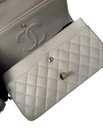 Load image into Gallery viewer, Close-up of a Chanel handbag with quilted design and gold hardware.
