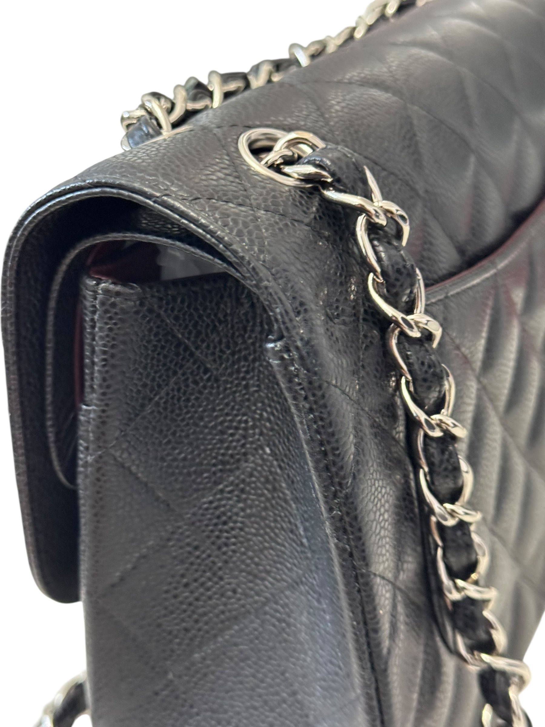 Close-up of a black quilted handbag with a chain detail on a white background