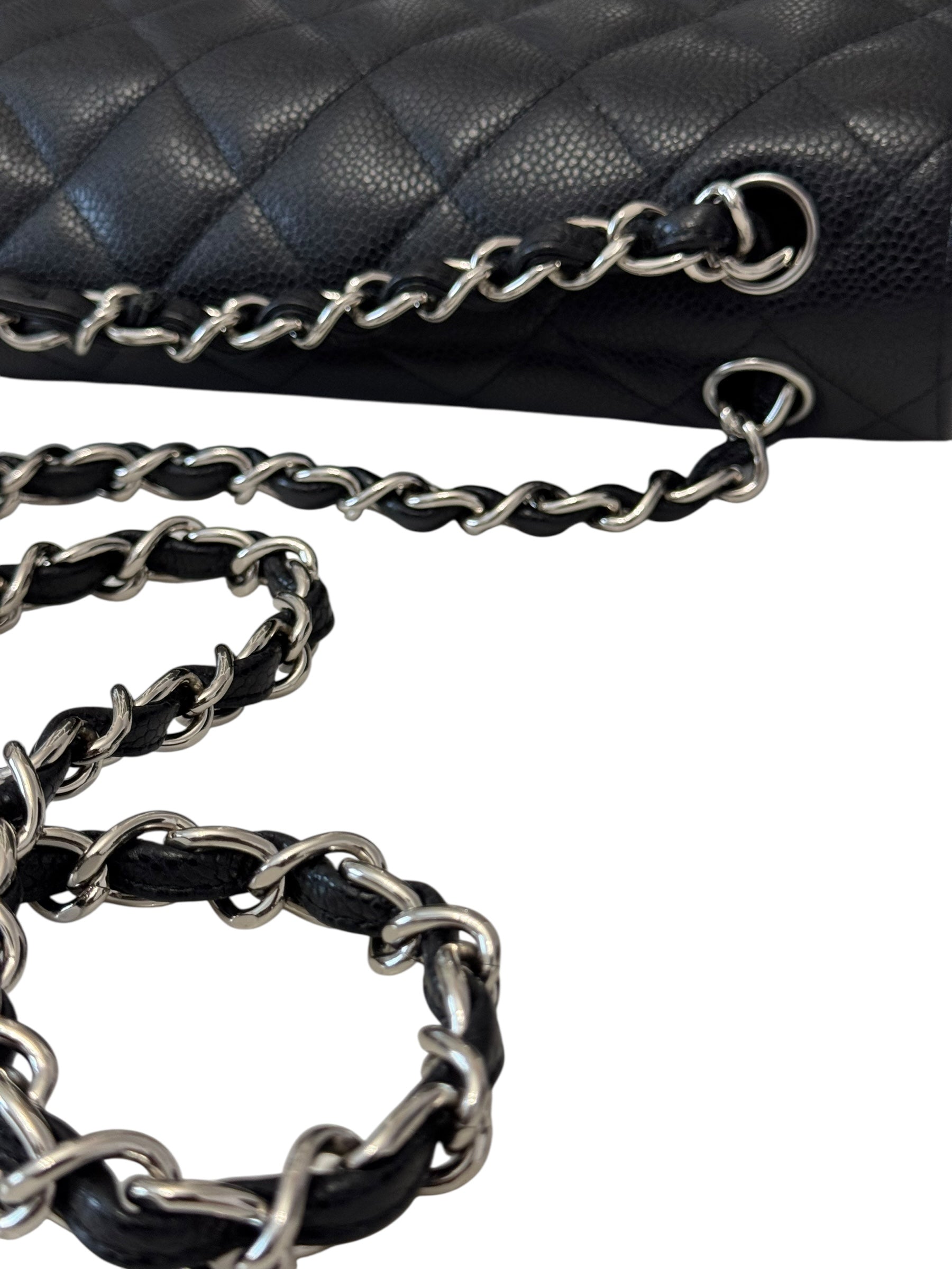 Close-up of a black quilted handbag with silver chain strap on a white background
