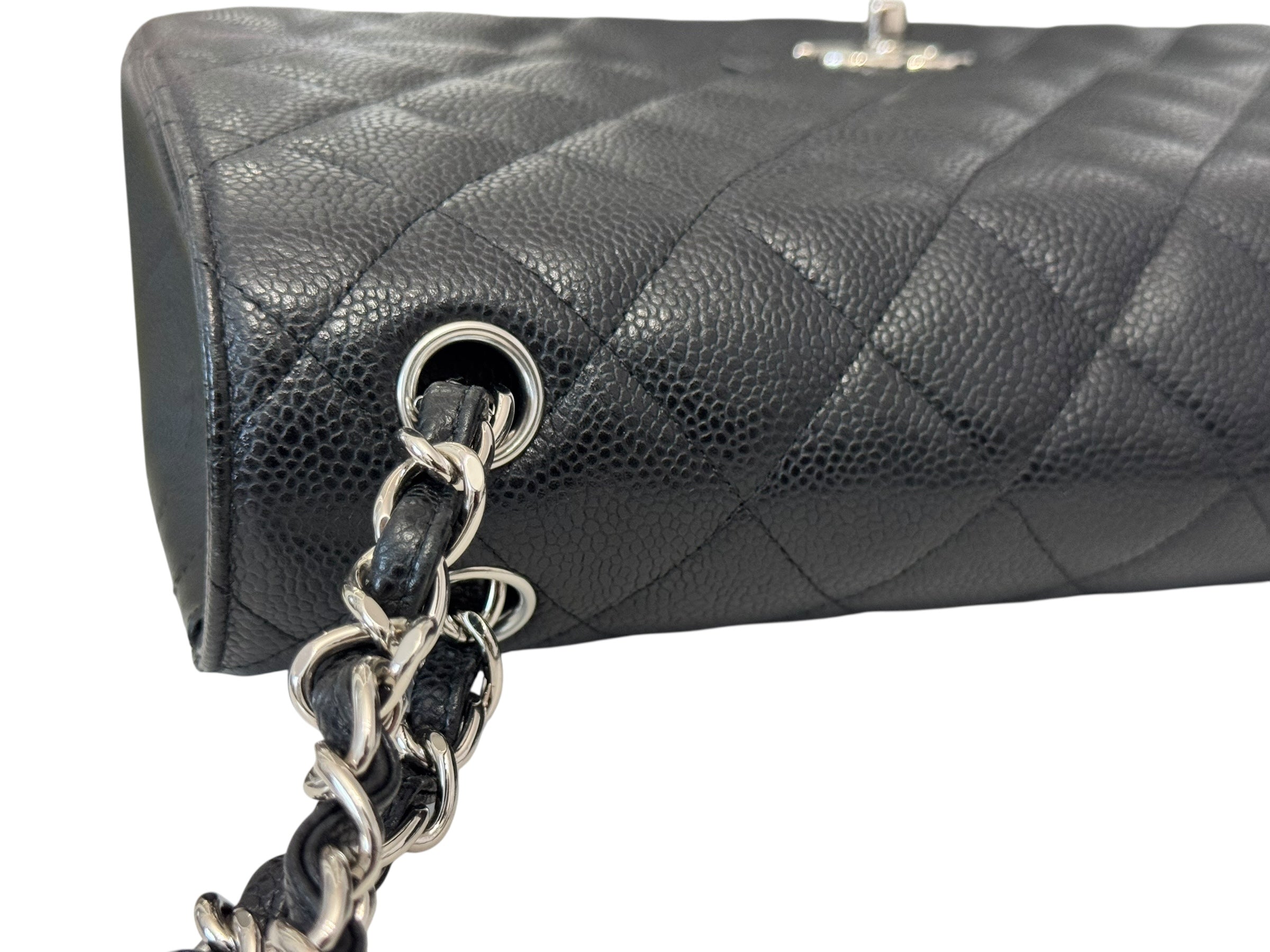 Black quilted handbag with a chain detail on a white background
