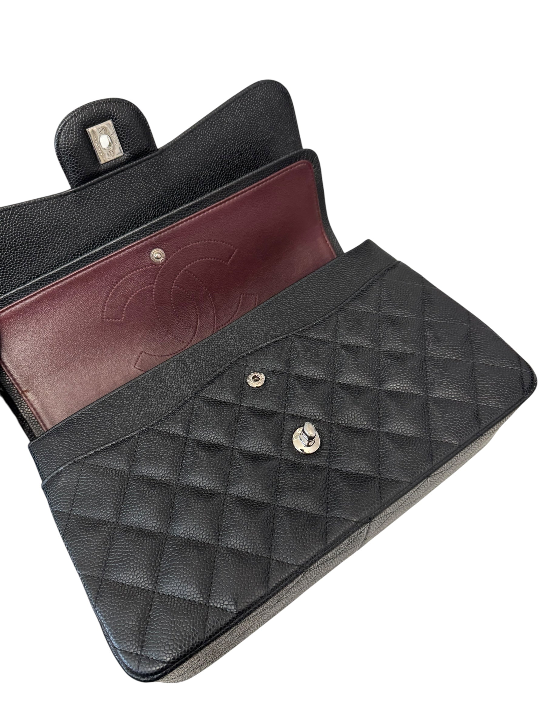 Black quilted handbag with a burgundy interior on a white background