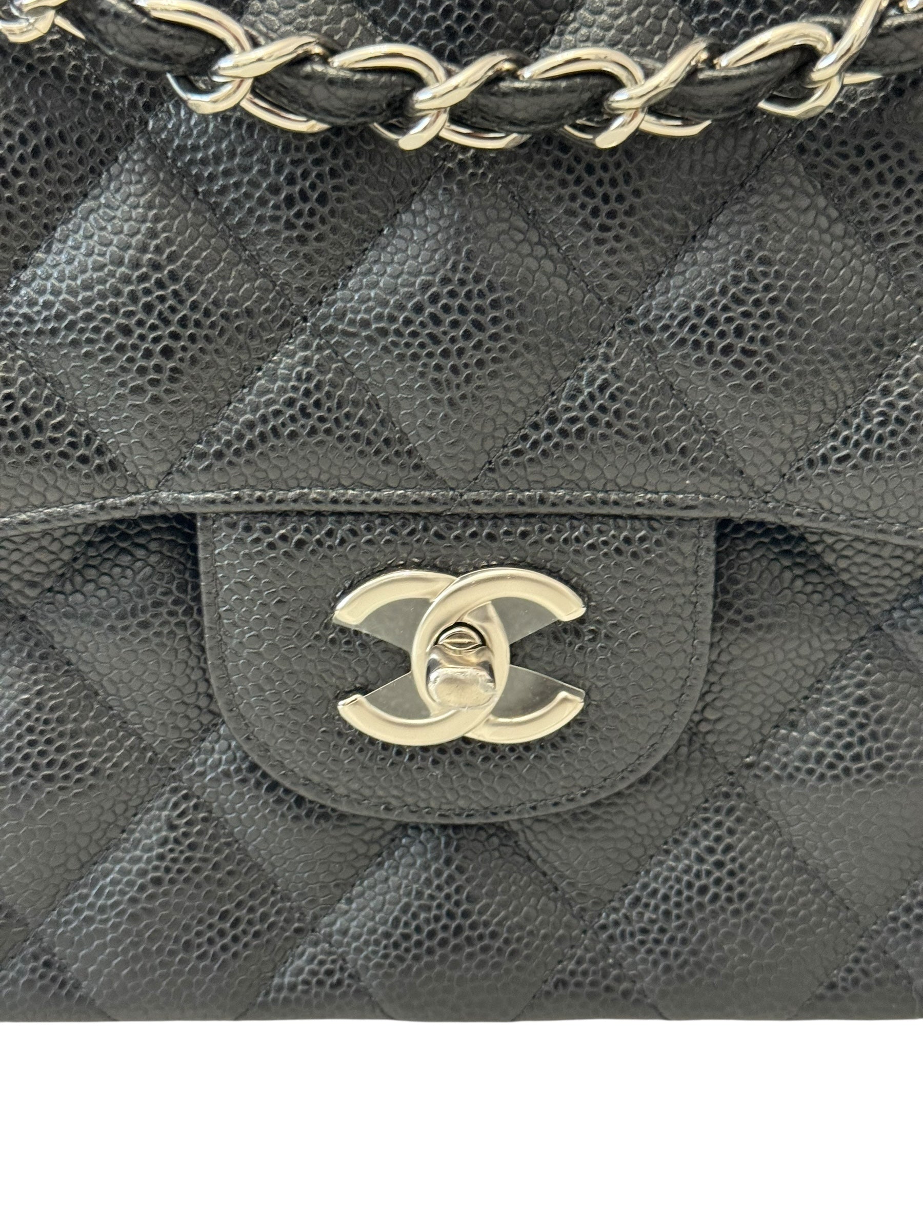 Close-up of a black quilted handbag with gold chain and CC logo.