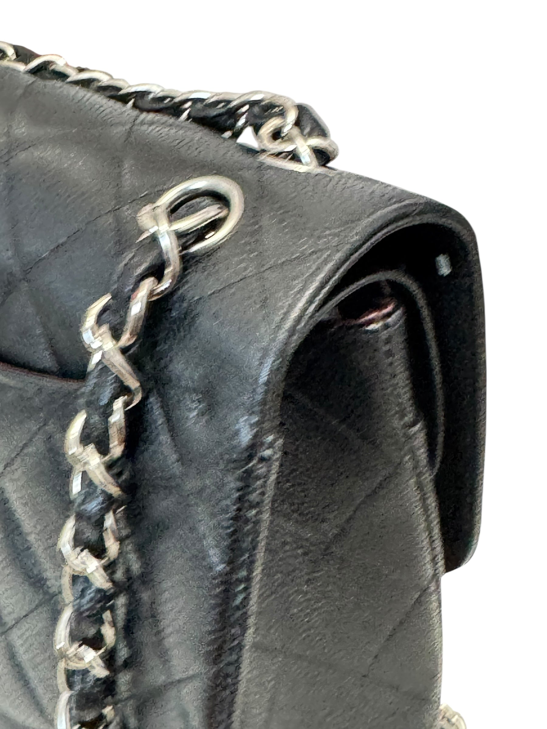 Black quilted handbag with silver chain detail on a white background