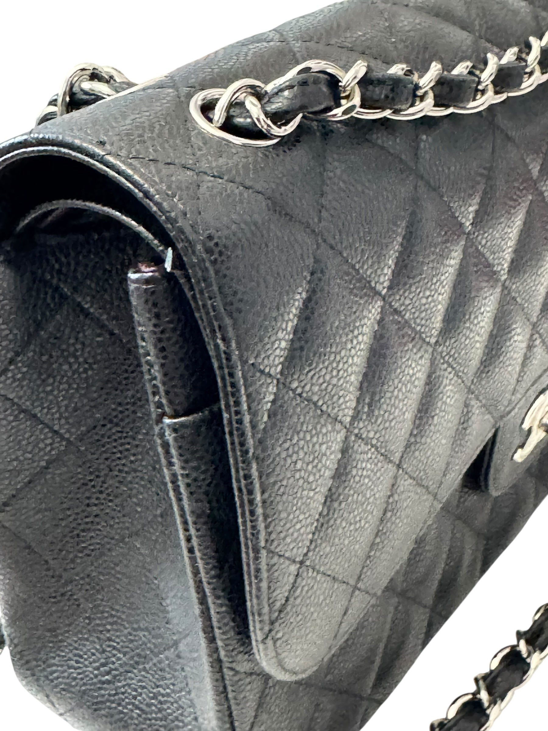 Close-up of a quilted gray handbag with a chain strap on a white background