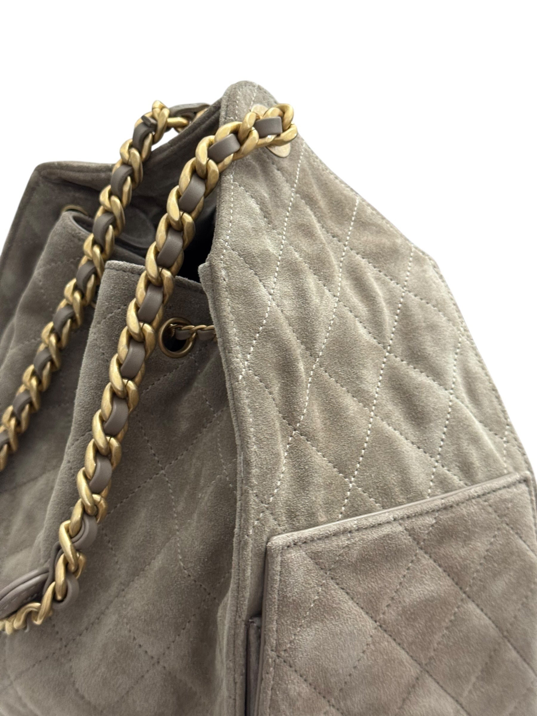 Gray quilted handbag with gold chain detail on a white background