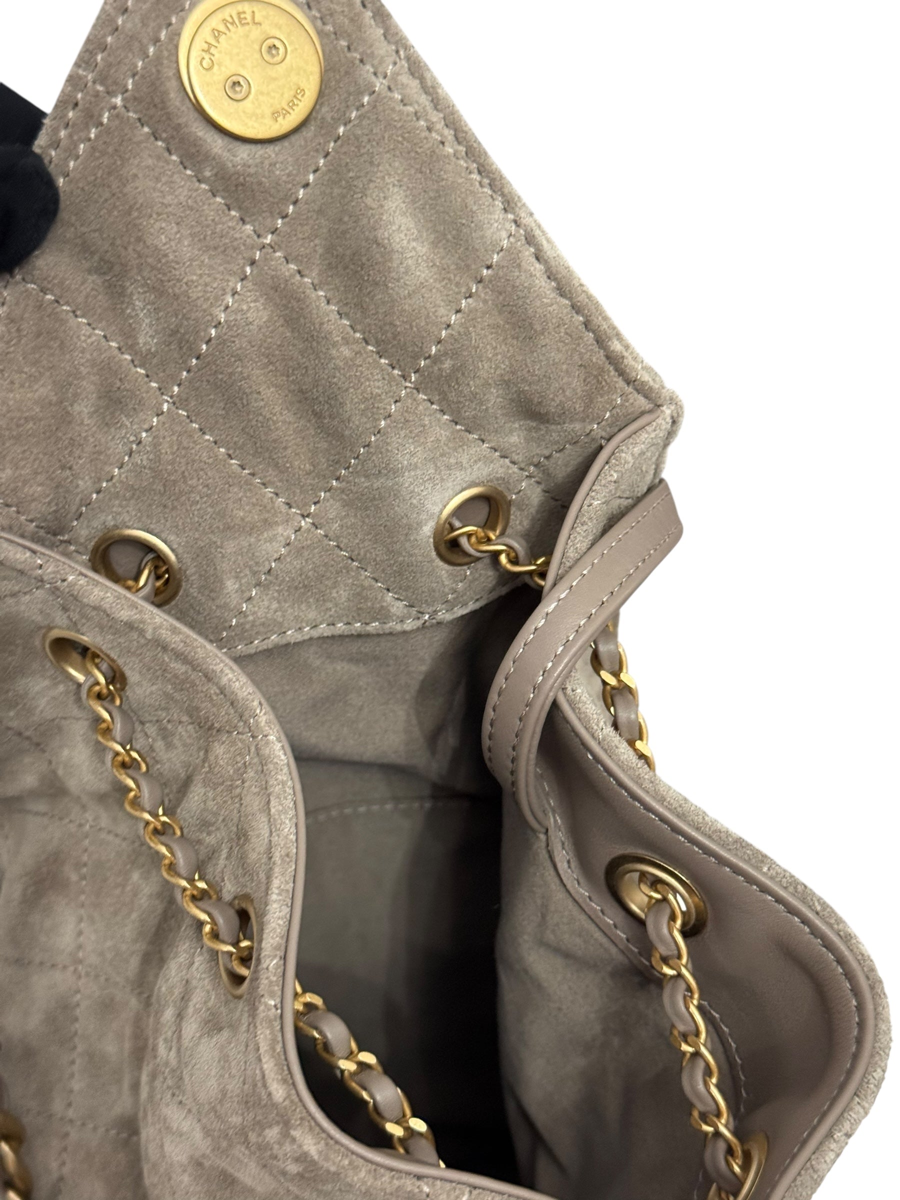 Close-up of a gray quilted handbag with gold hardware on a white background