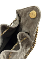 将图片加载到图库查看器，Gray suede handbag with gold chain and button detail on a white background
