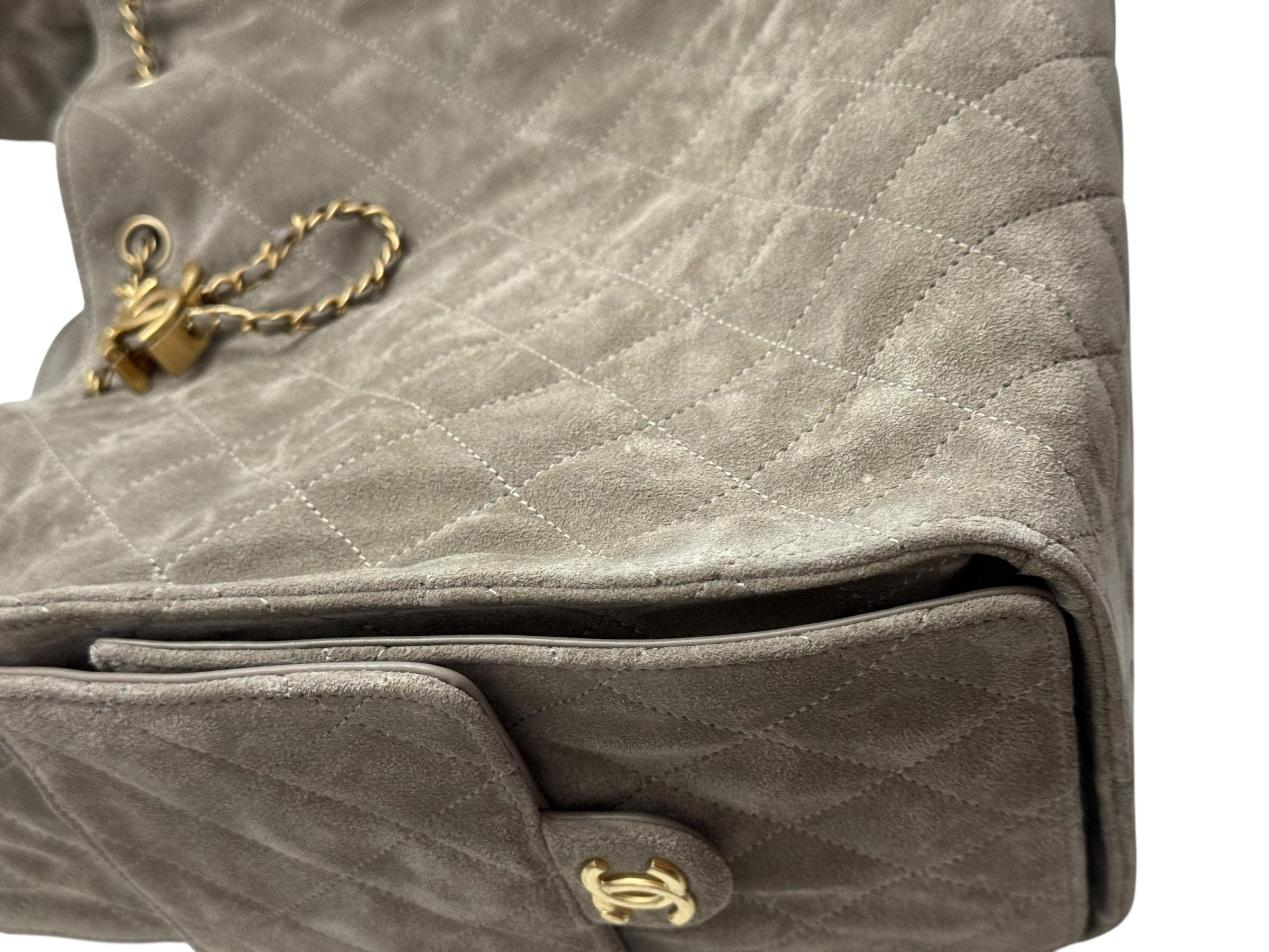 Close-up of a quilted gray handbag with gold hardware on a white background