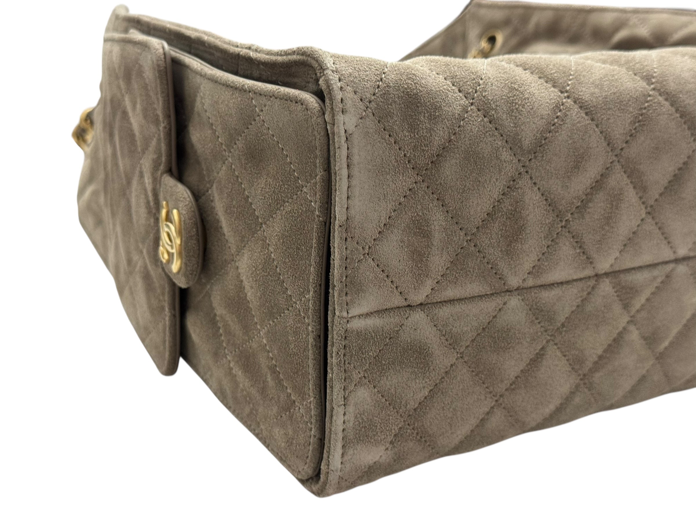 Quilted beige handbag with gold hardware on a white background