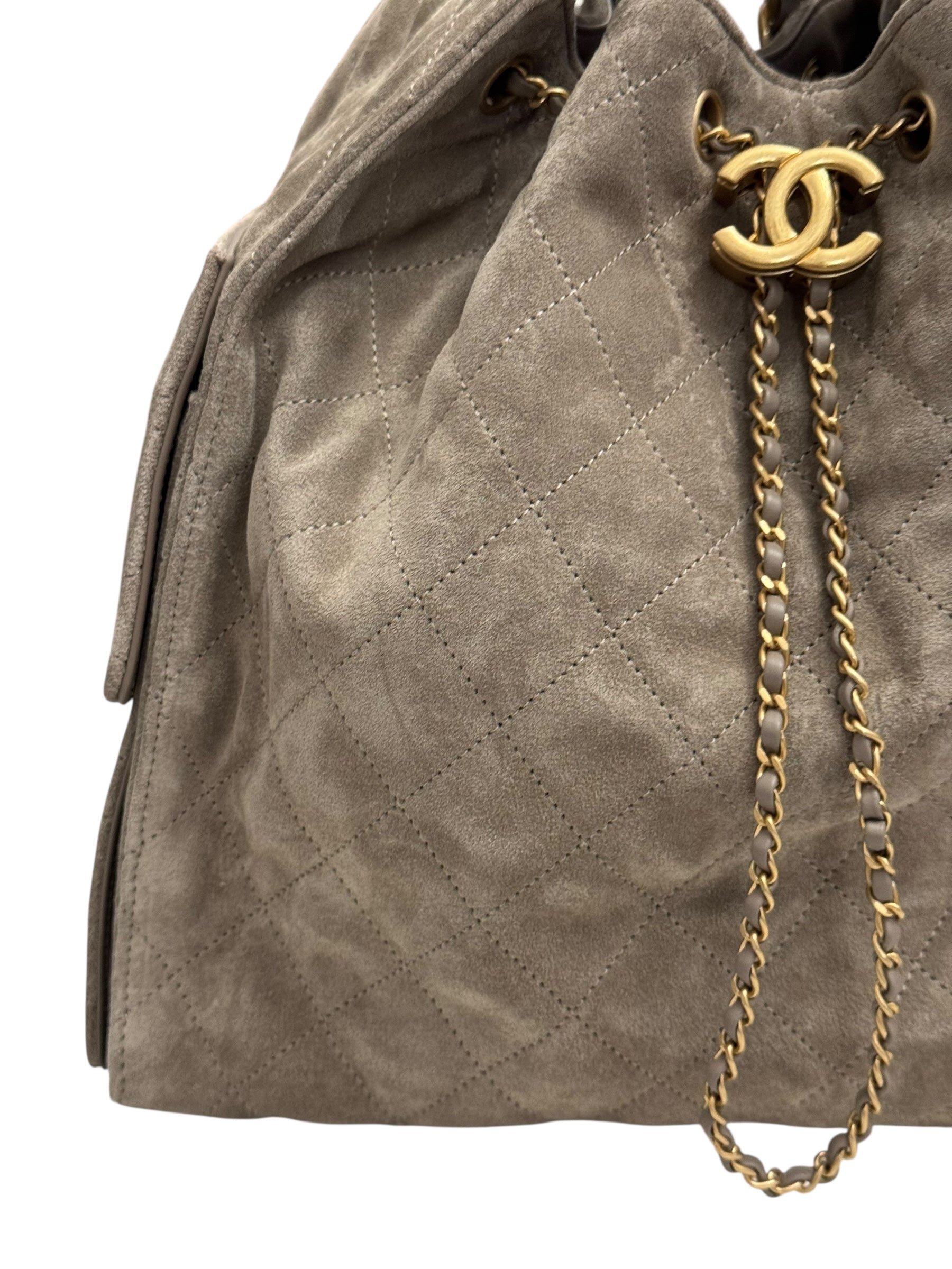 Quilted beige handbag with gold chain and Chanel logo on a white background