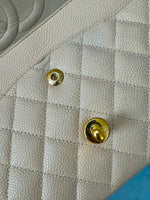Load image into Gallery viewer, Close-up of a quilted leather surface with gold buttons.
