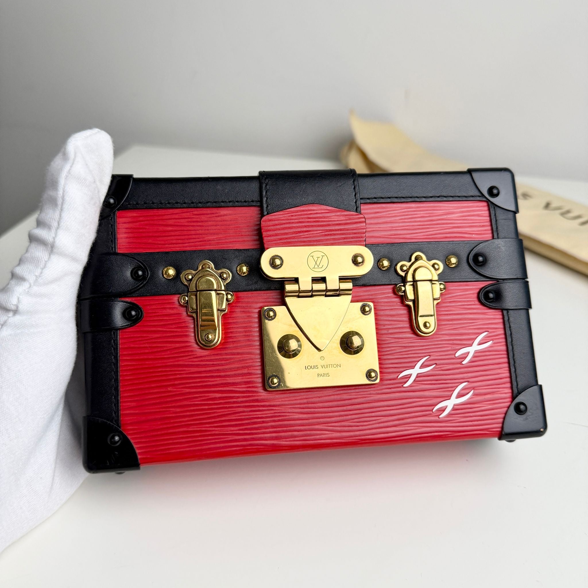 Red and black trinket box with gold accents on a white surface