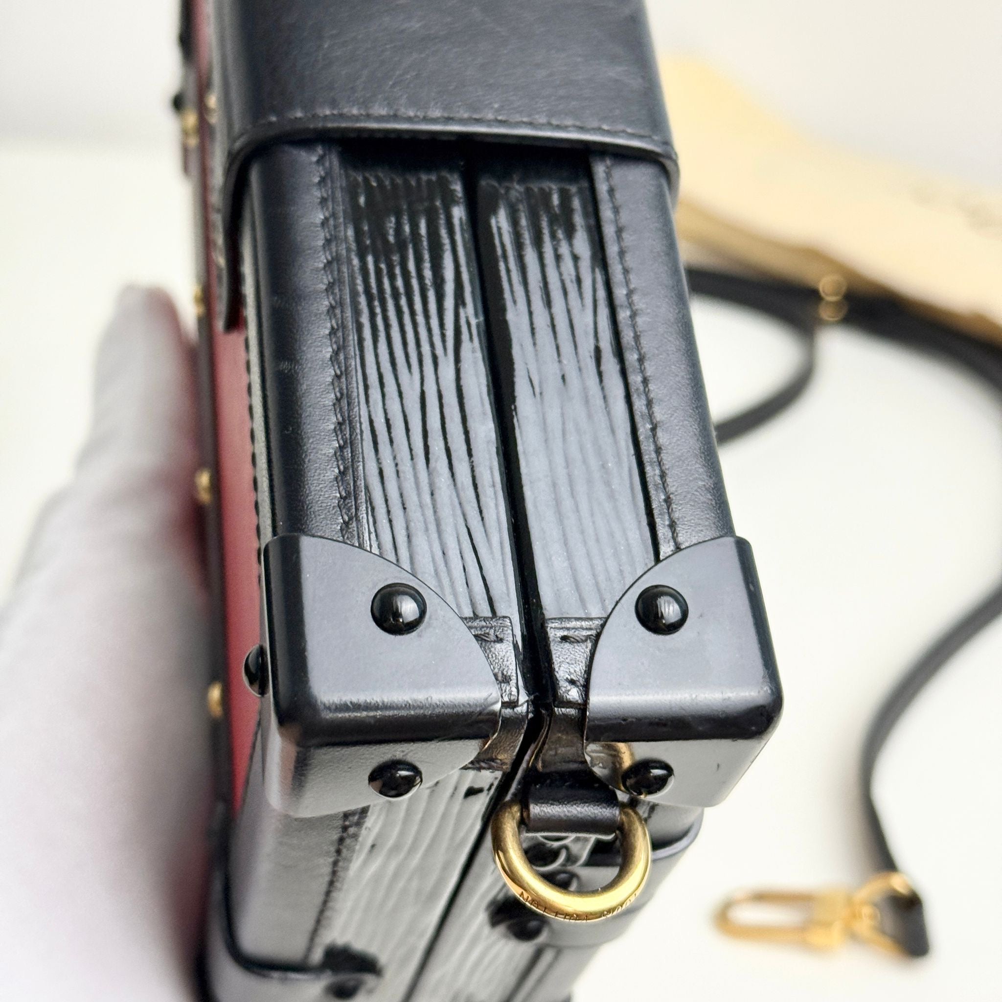 Close-up of a black leather wallet with a gold ring on a white background