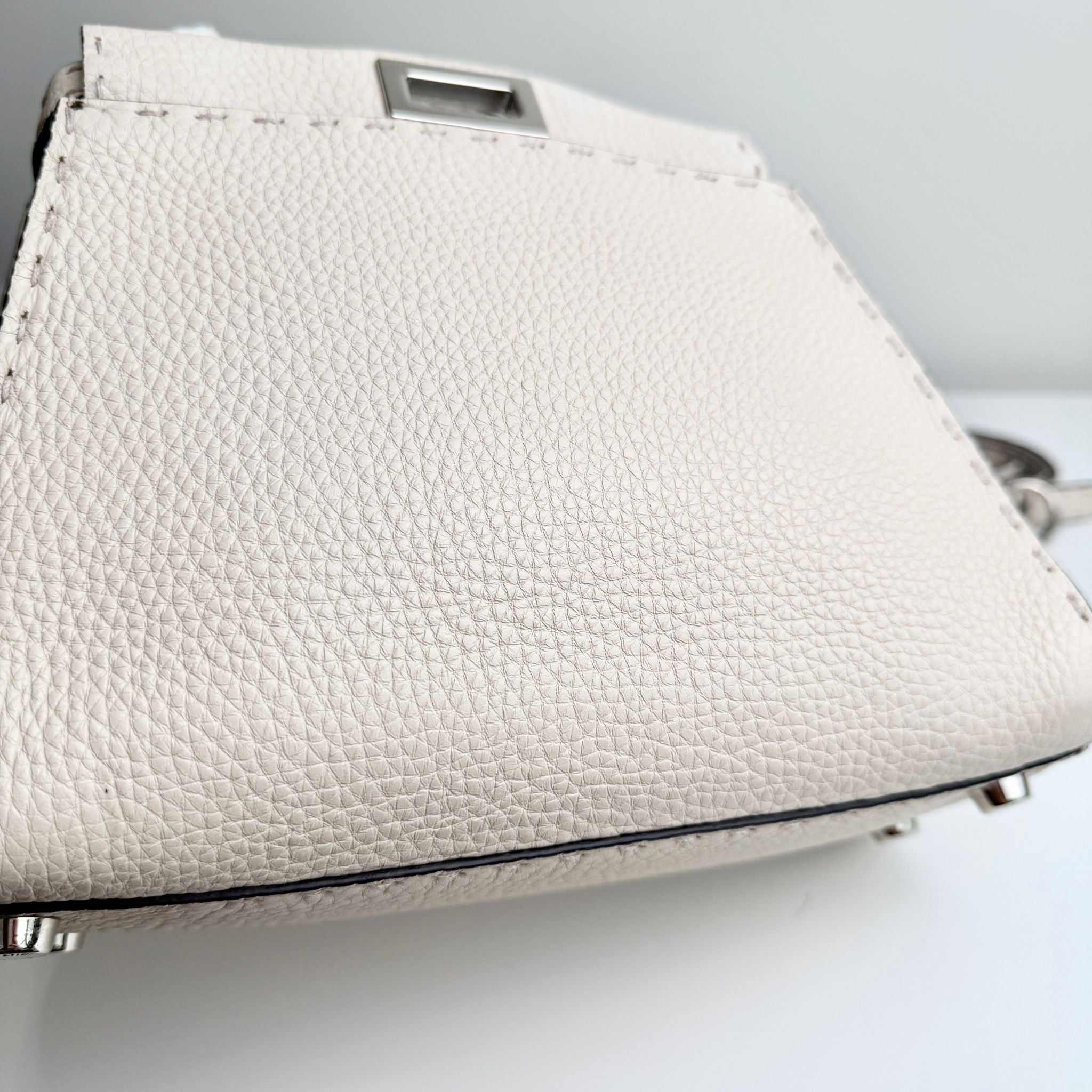 Close-up of a textured white handbag on a light gray background