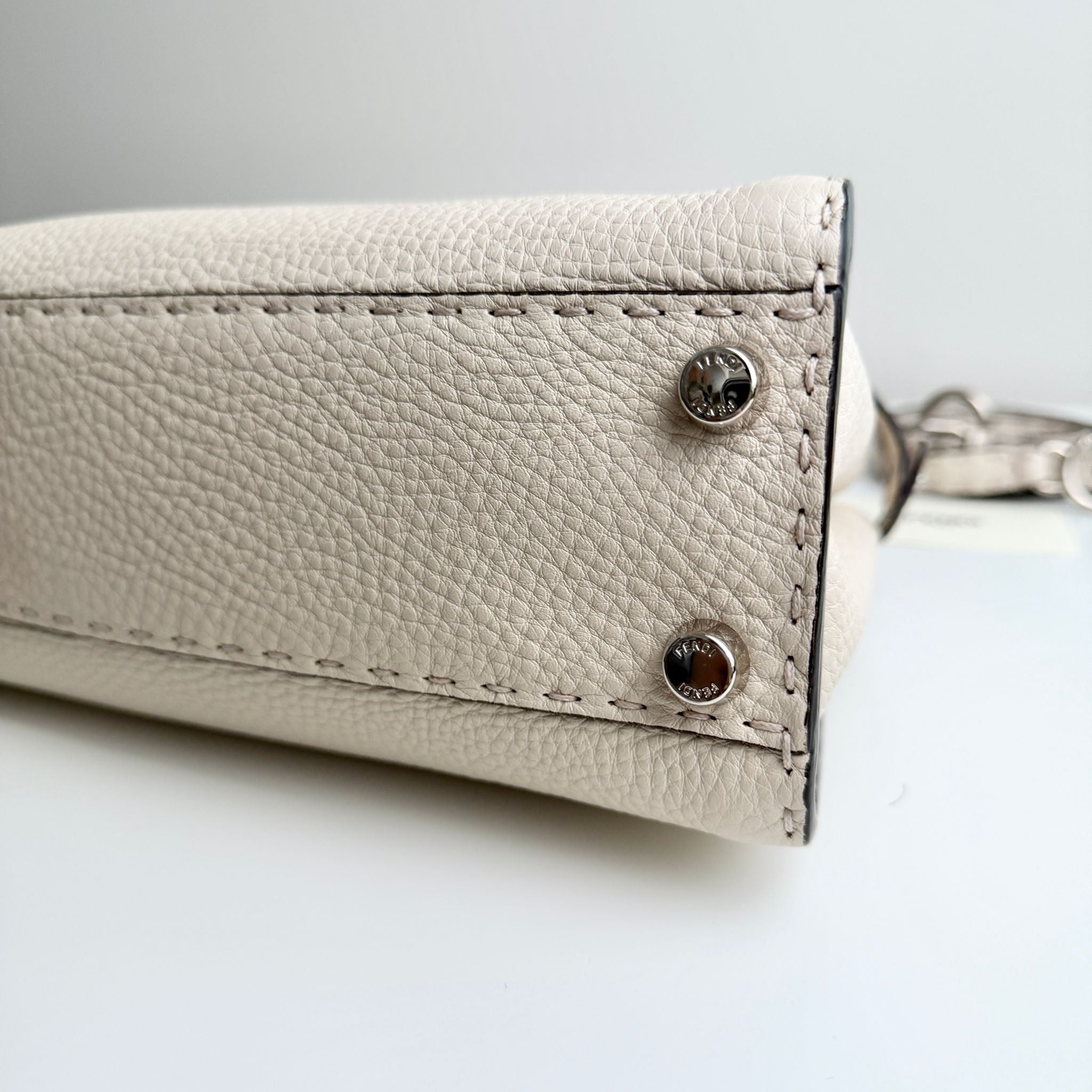 Close-up of a beige leather wallet with metal accents on a light gray background