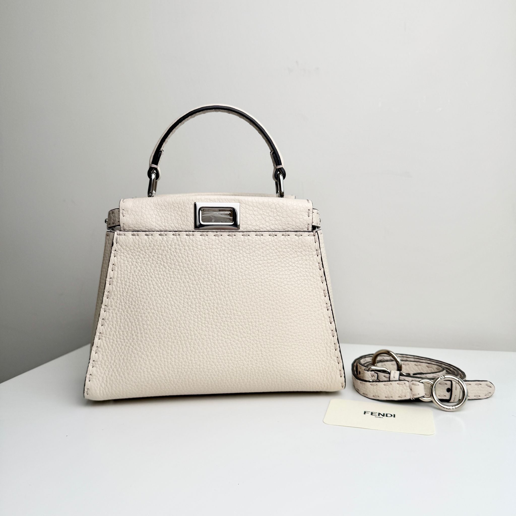 White handbag with matching belt on a light gray background