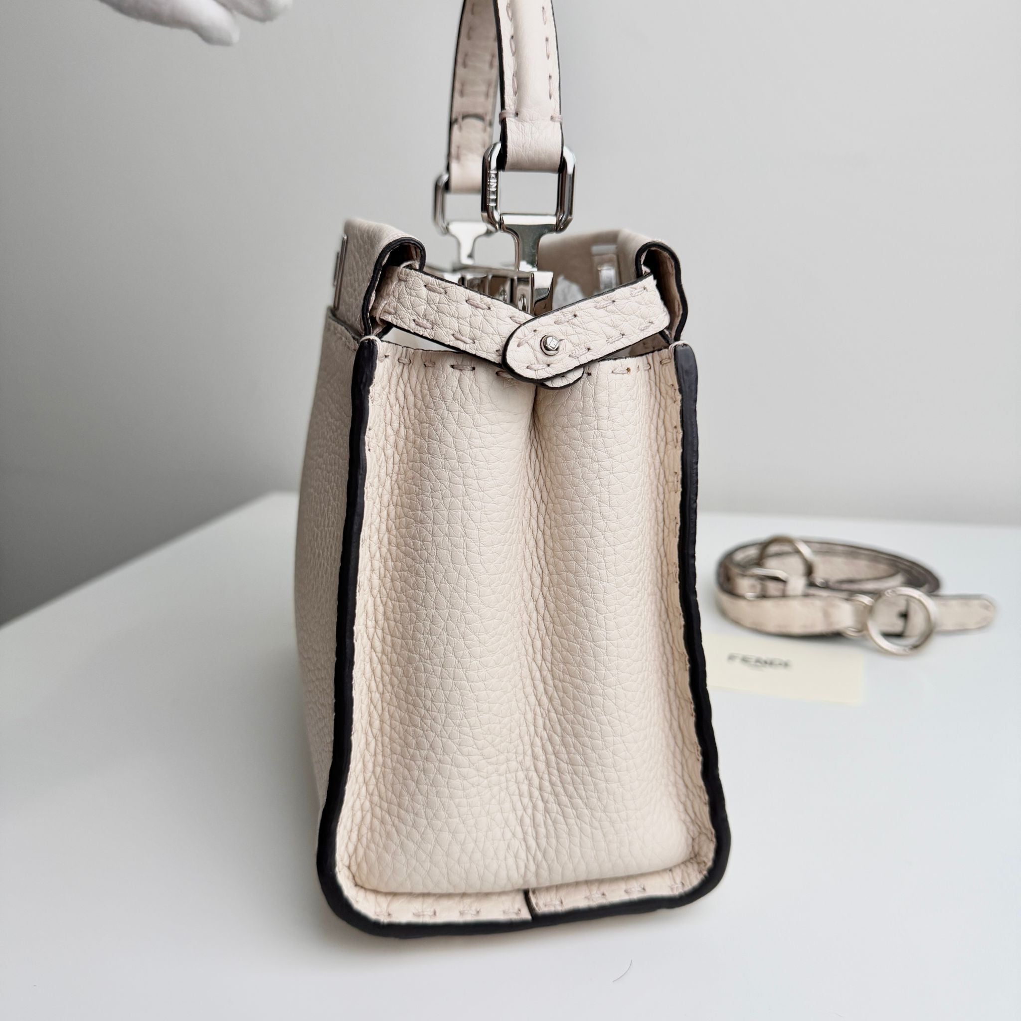 Beige handbag with black trim on a white surface