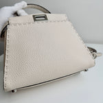 将图片加载到图库查看器，Beige handbag with a visible brand logo held by a gloved hand on a light gray background
