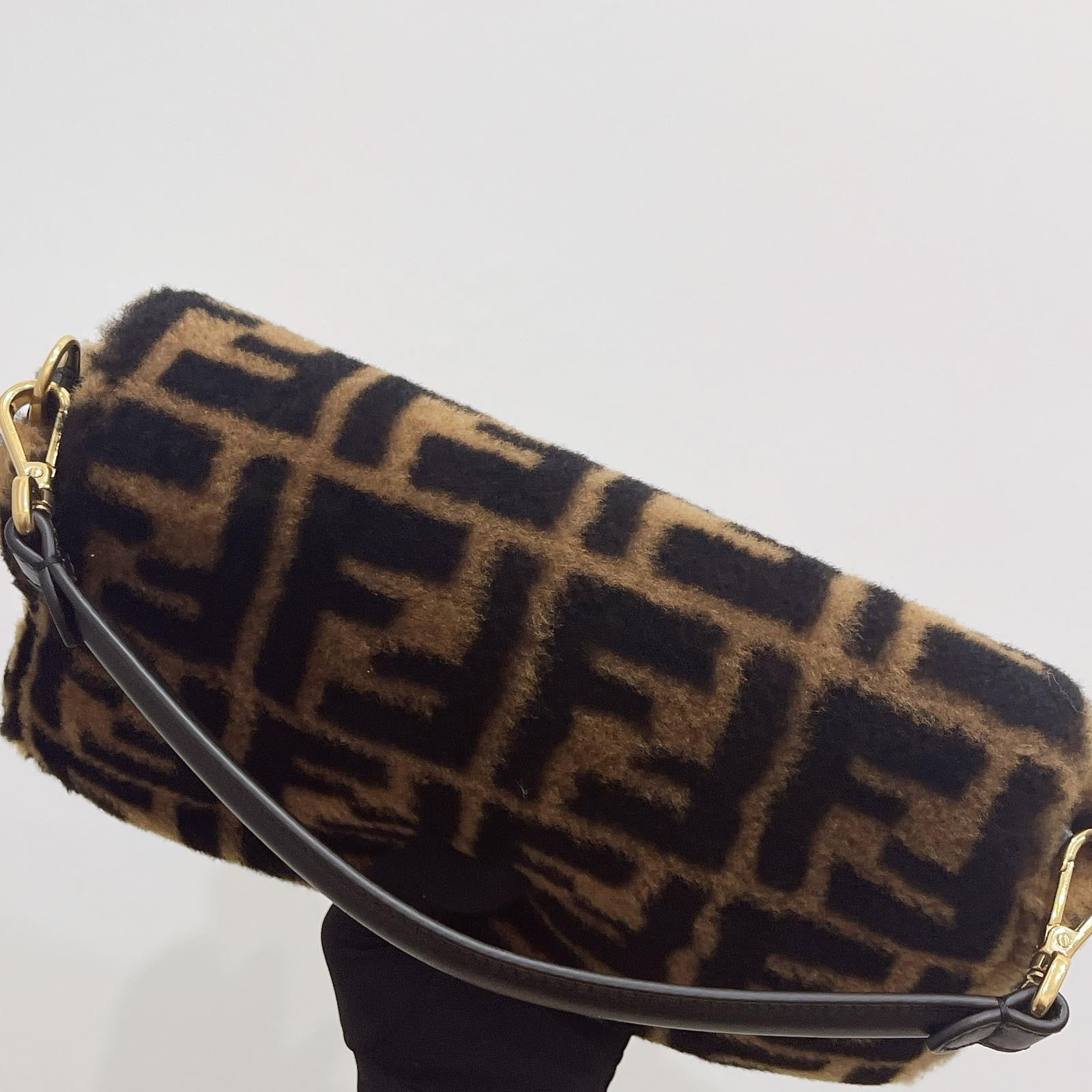 Designer handbag with recognizable logo pattern on a light gray background