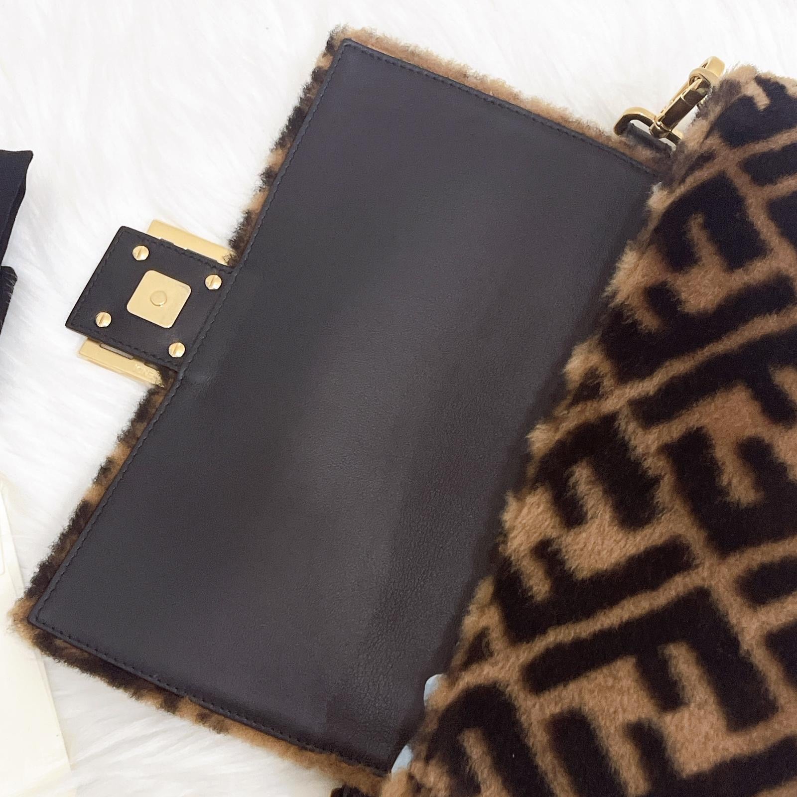 Black pouch with gold accents on a patterned fabric background