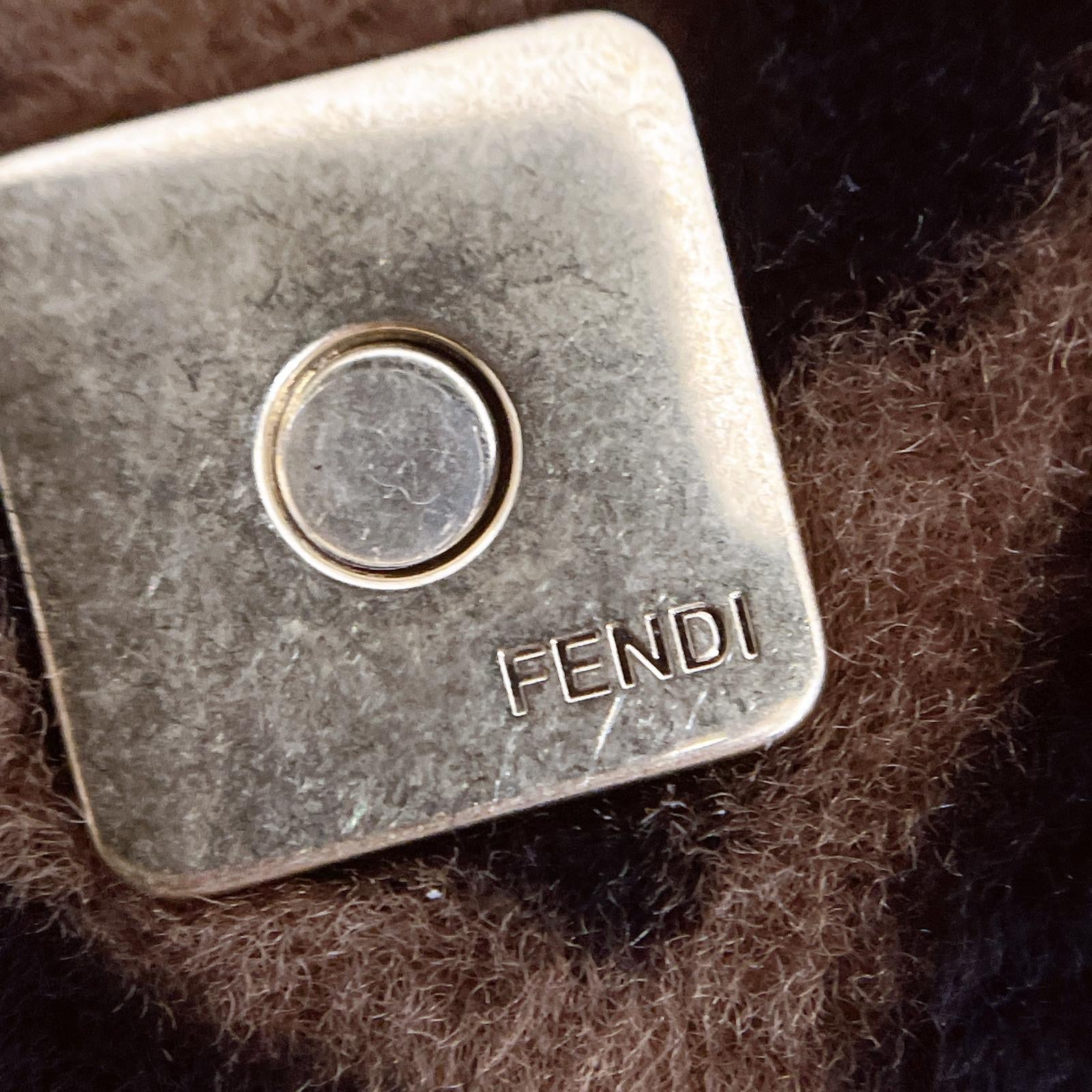 Fendi metal tag on a textured brown surface