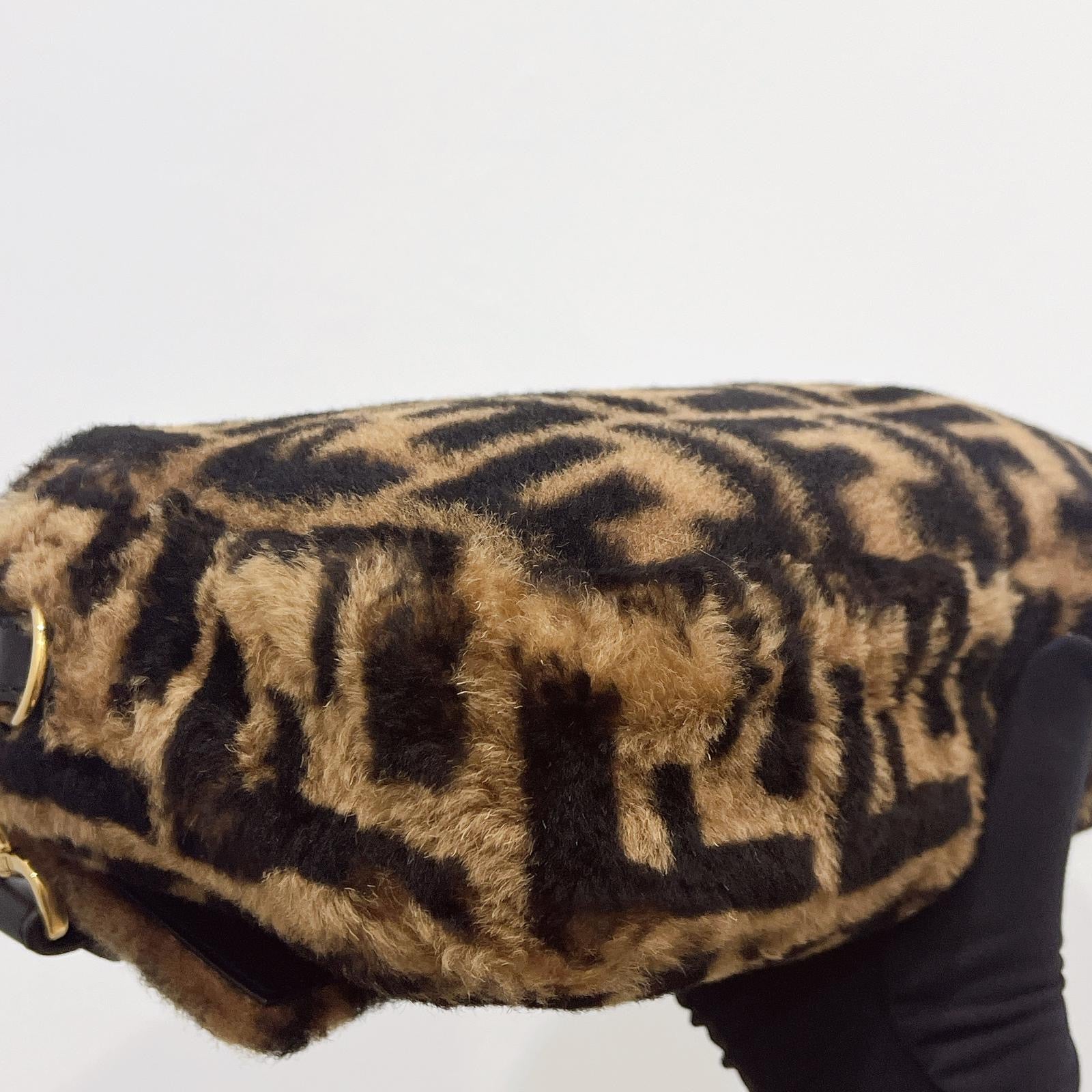 Leopard print clutch bag held by a hand on a white background