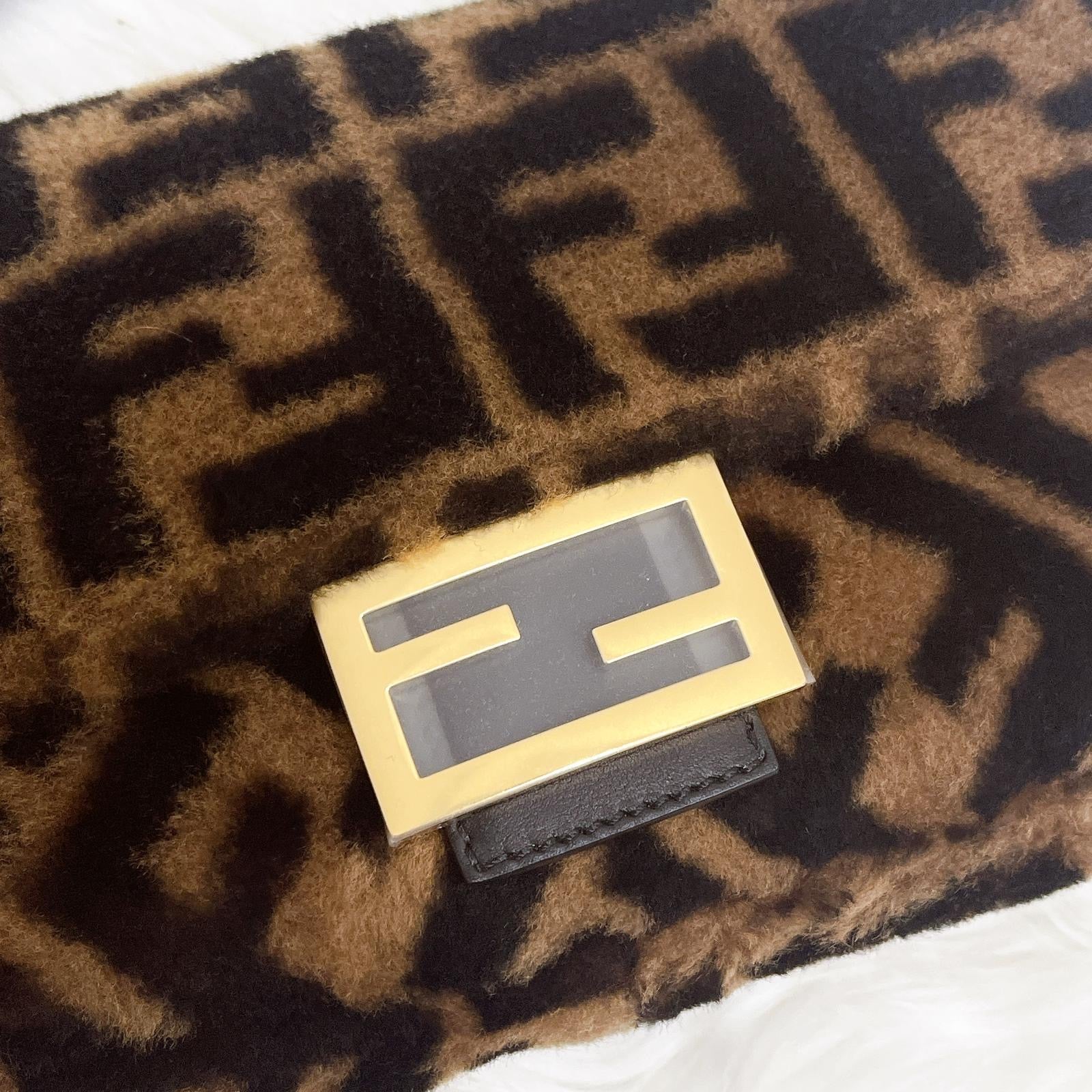 Gold and black Fendi logo on a patterned fabric background