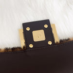 将图片加载到图库查看器，Close-up of a black leather clutch with gold hardware on a white fur background

