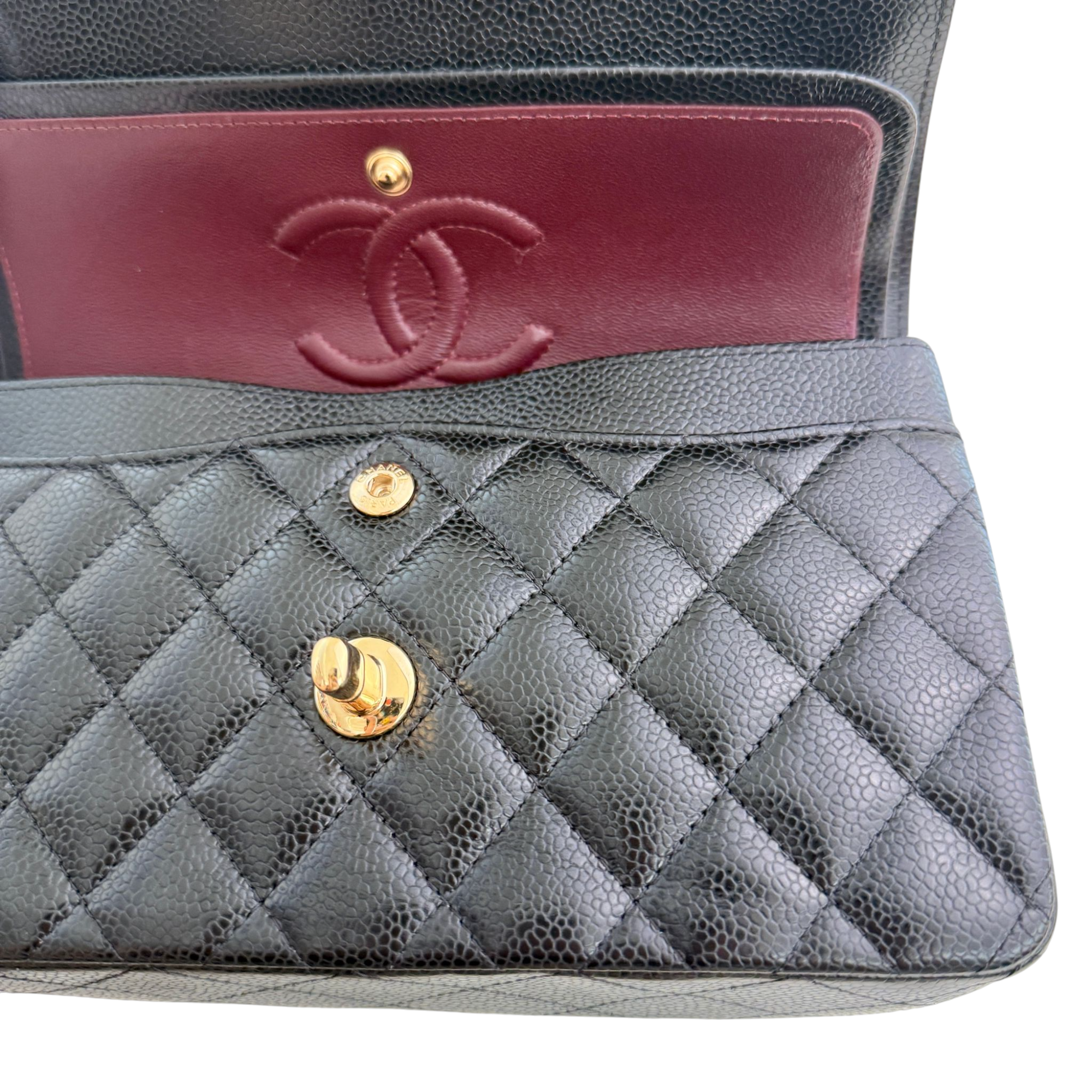 Gray quilted handbag with gold hardware and red interior showing Chanel logo.