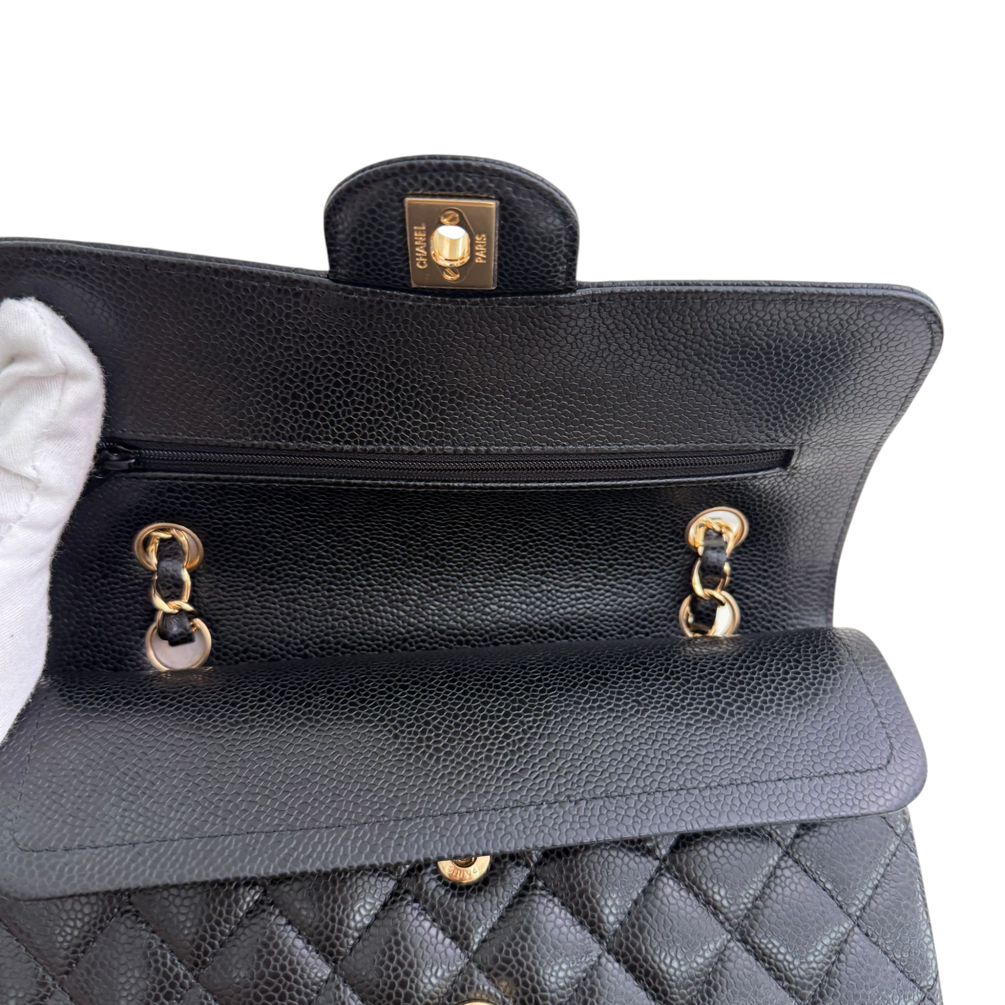 Black quilted handbag with gold hardware on a white background