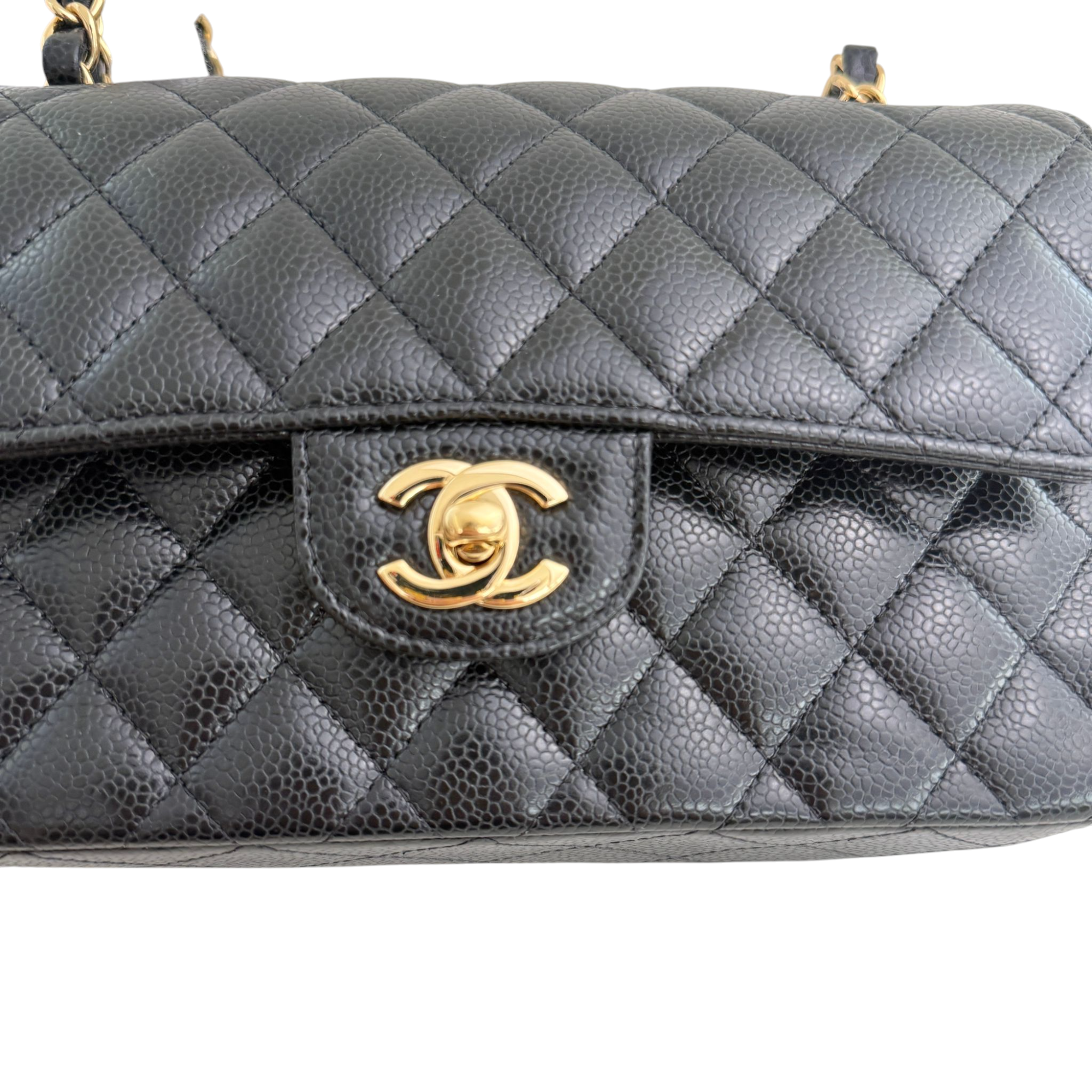 Black quilted handbag with gold clasp on a white background
