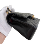 Charger l&#39;image dans la galerie, Black quilted handbag held by a gloved hand on a white background
