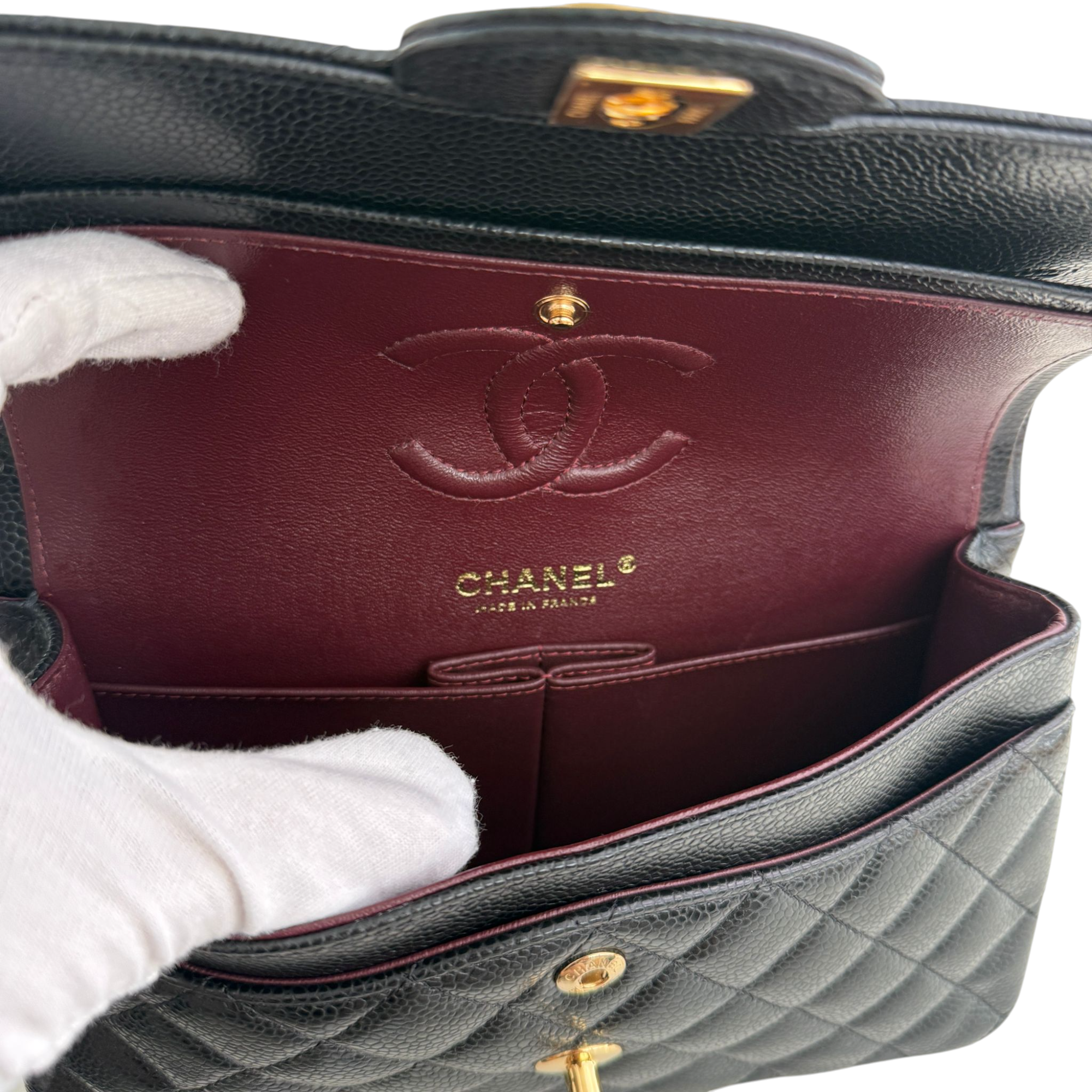 Chanel handbag with open interior showing quilted design and brand logo.