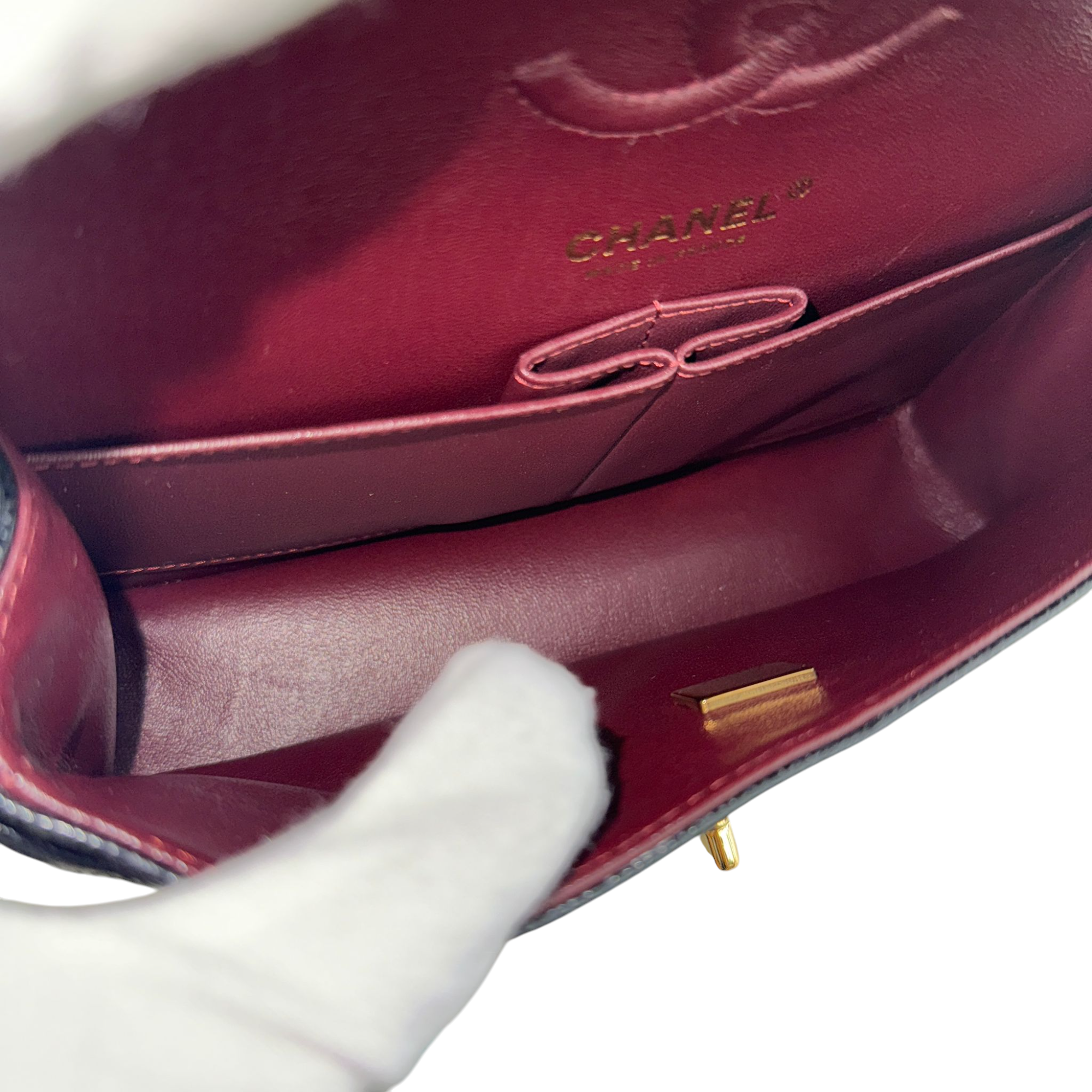 Close-up of a Chanel handbag with a white glove holding it open.