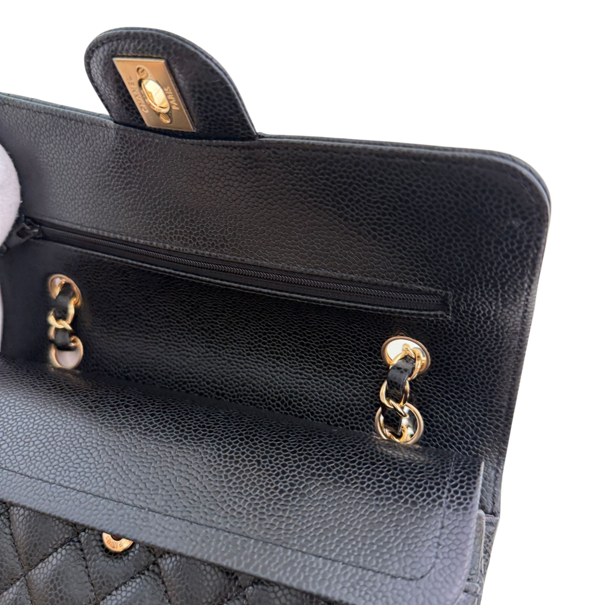 Close-up of a black handbag with gold hardware on a white background