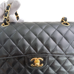 Charger l&#39;image dans la galerie, Quilted black handbag with gold hardware held by a gloved hand.
