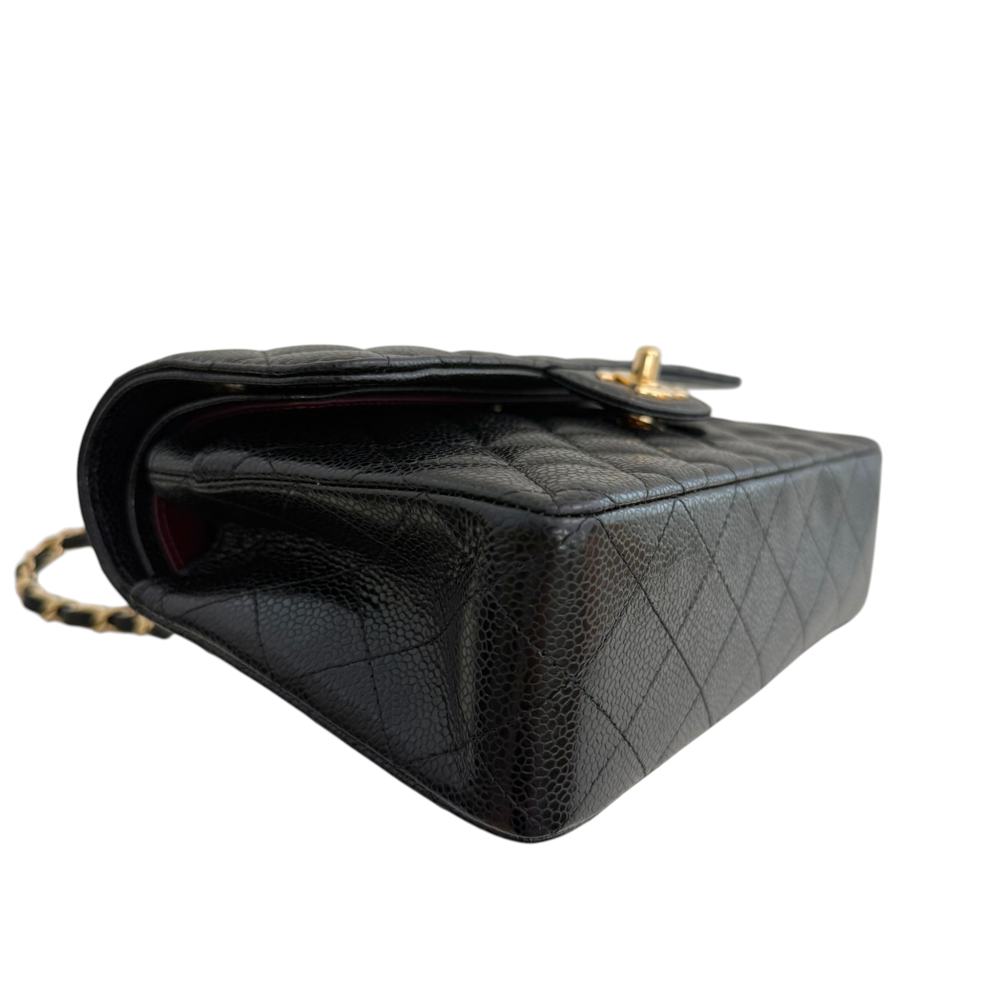 Black quilted handbag with gold hardware on a white background