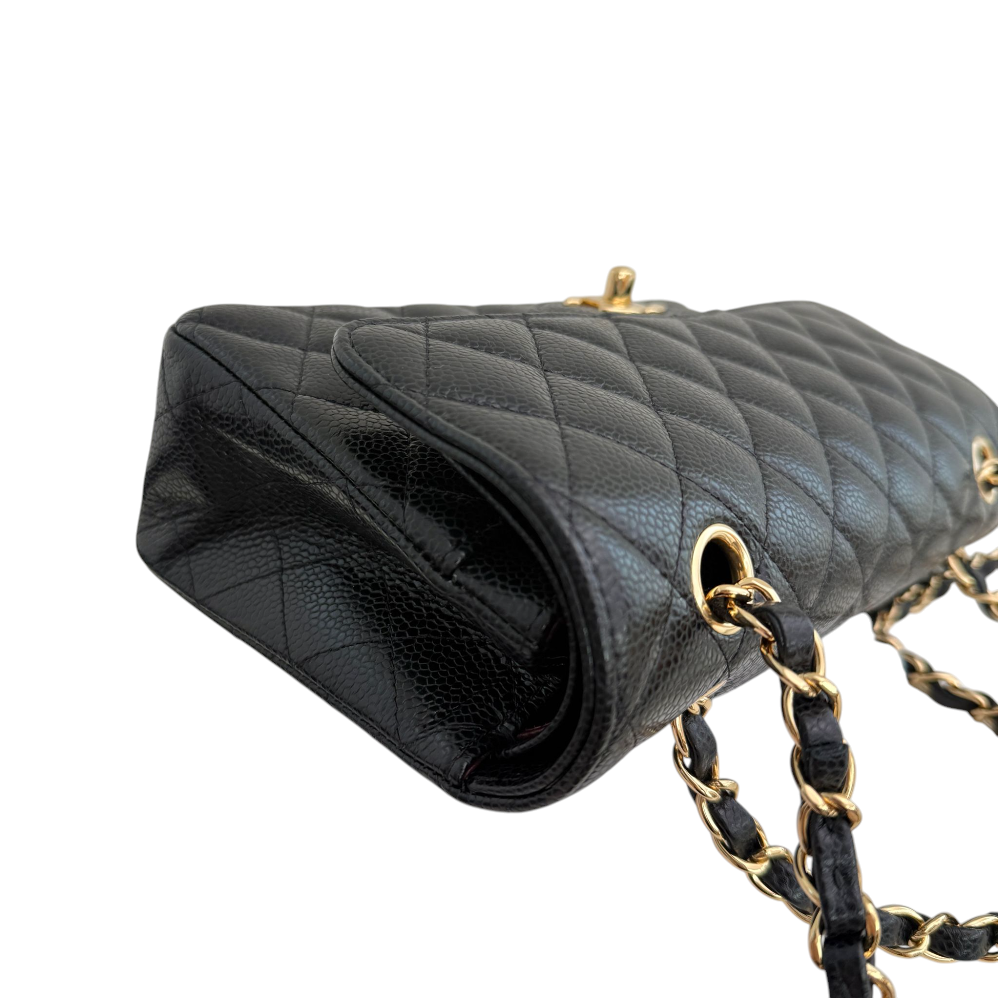 Black quilted handbag with gold chain strap on a white background